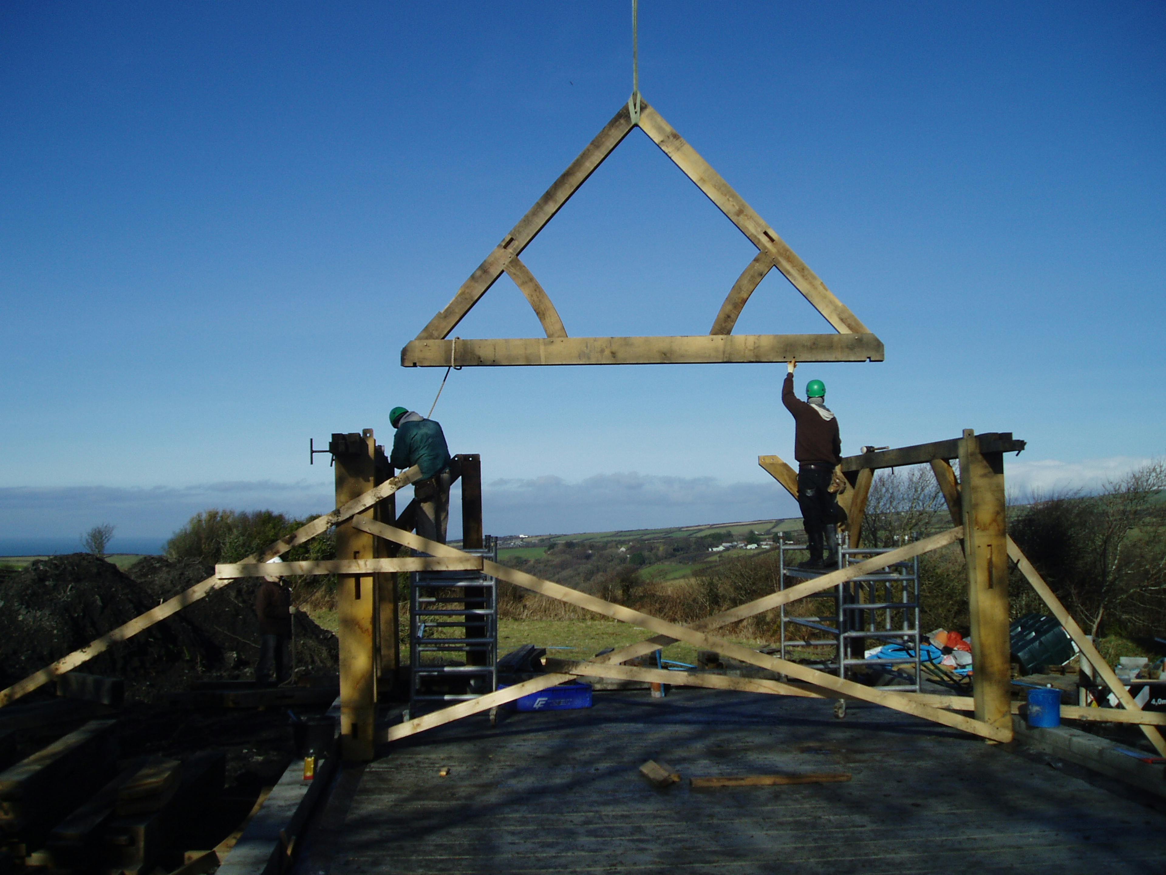Installation of an oak-framed single-storey house, using a crane to lift a preassembled truss into position