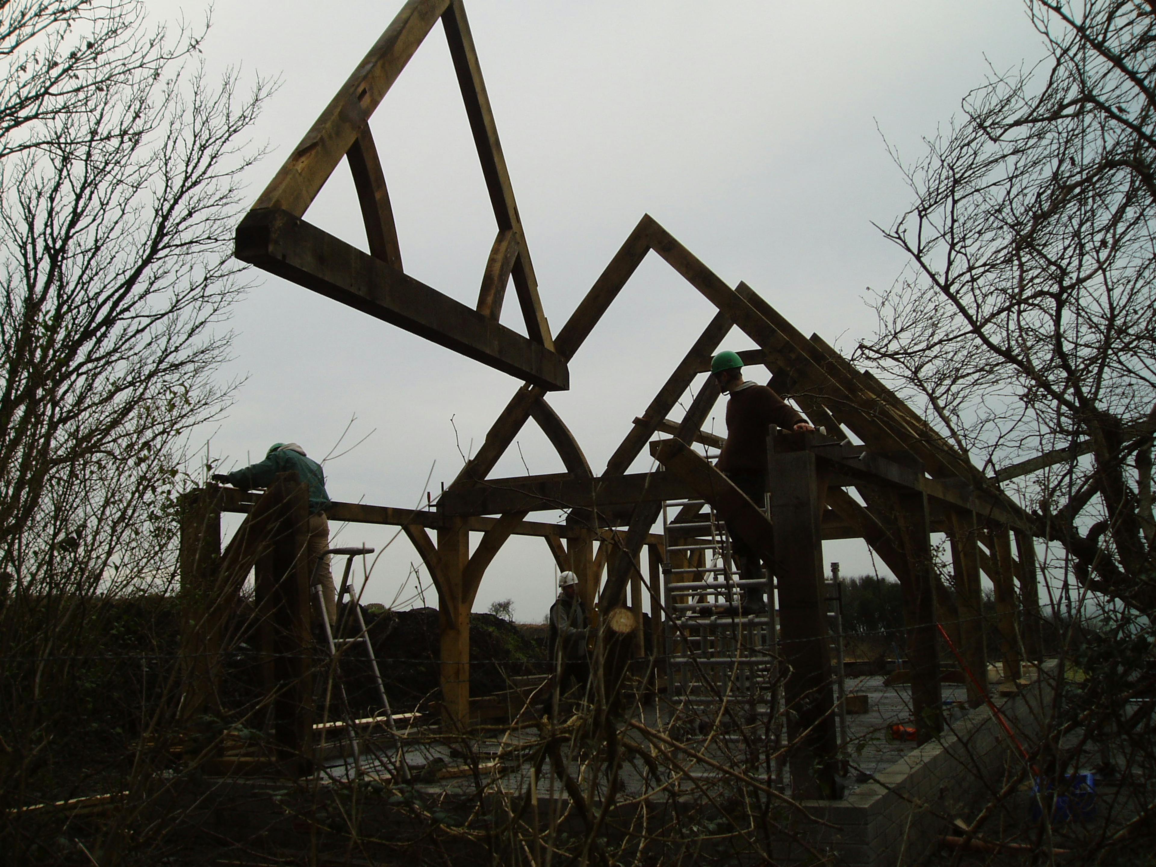 Installation of an oak-framed house, using a crane to lift a preassembled truss into position