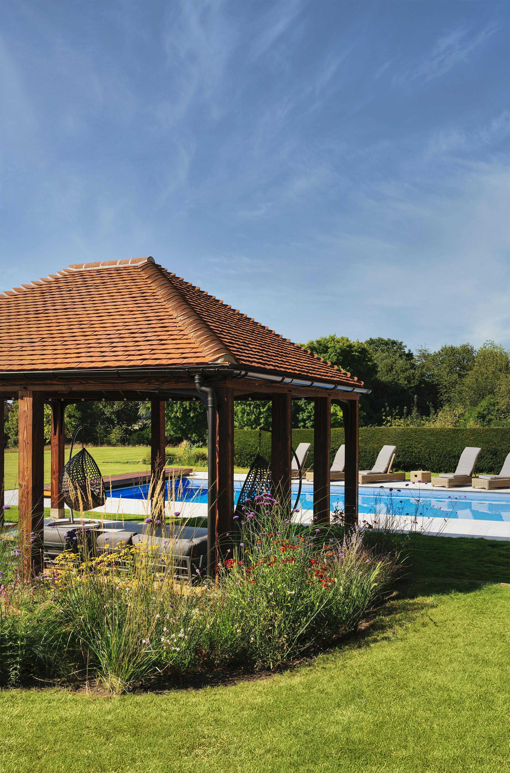 A charred Douglas fir framed garden annexe by a swimming pool