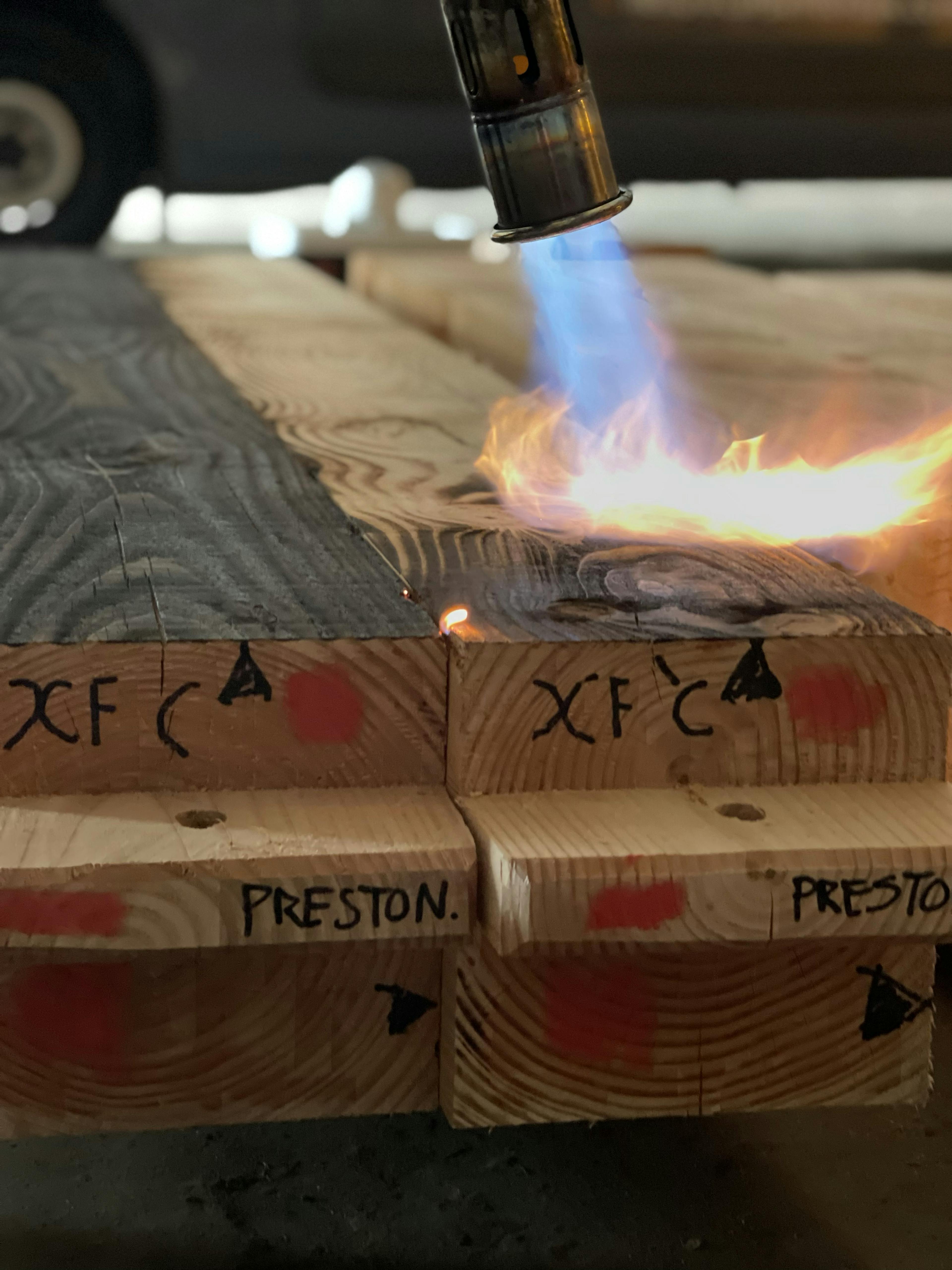 A fire torch chars a piece of Douglas fir timber in a workshop