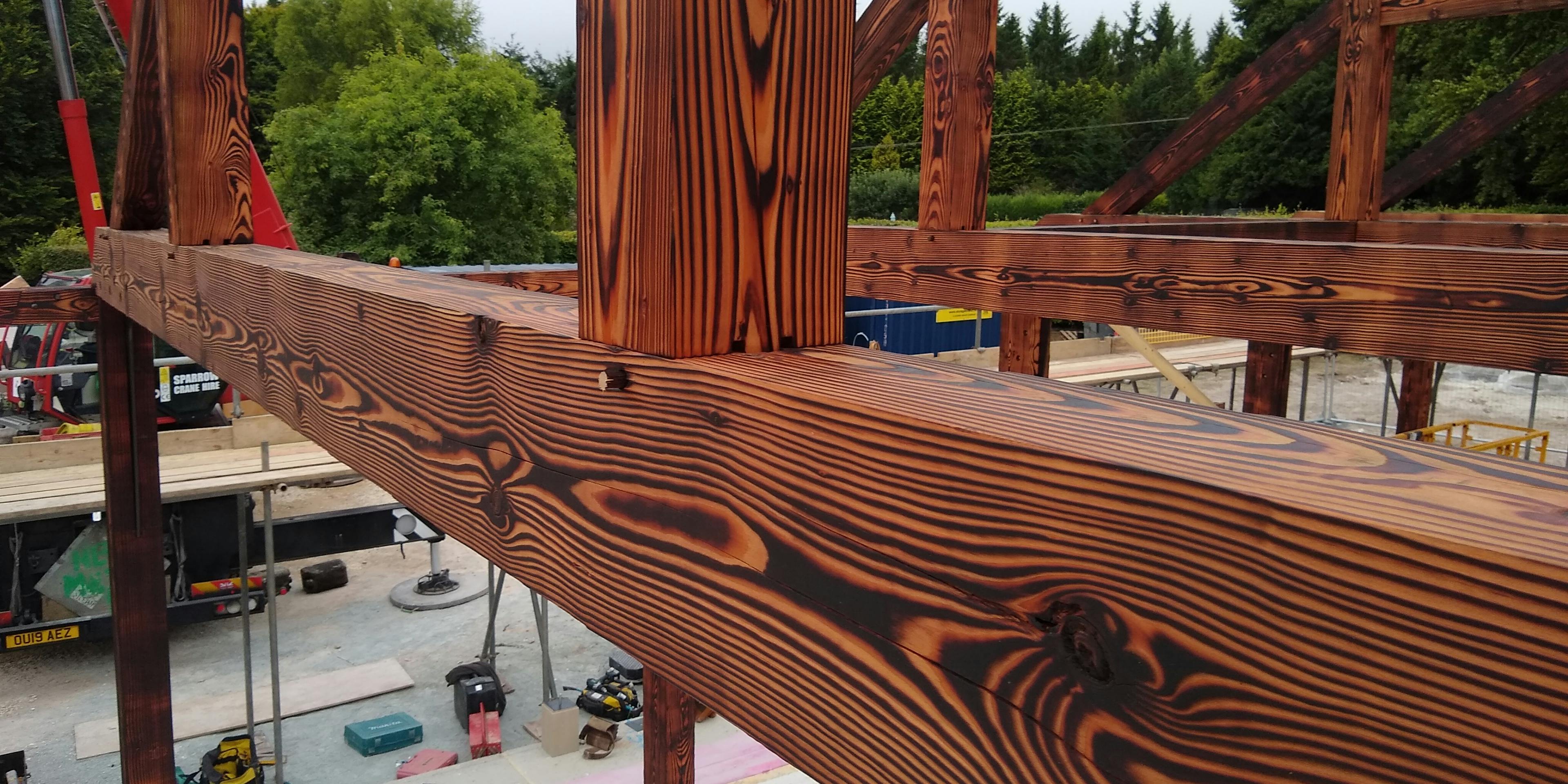 Close up image of a charred Douglas fir framed garden annex during installation