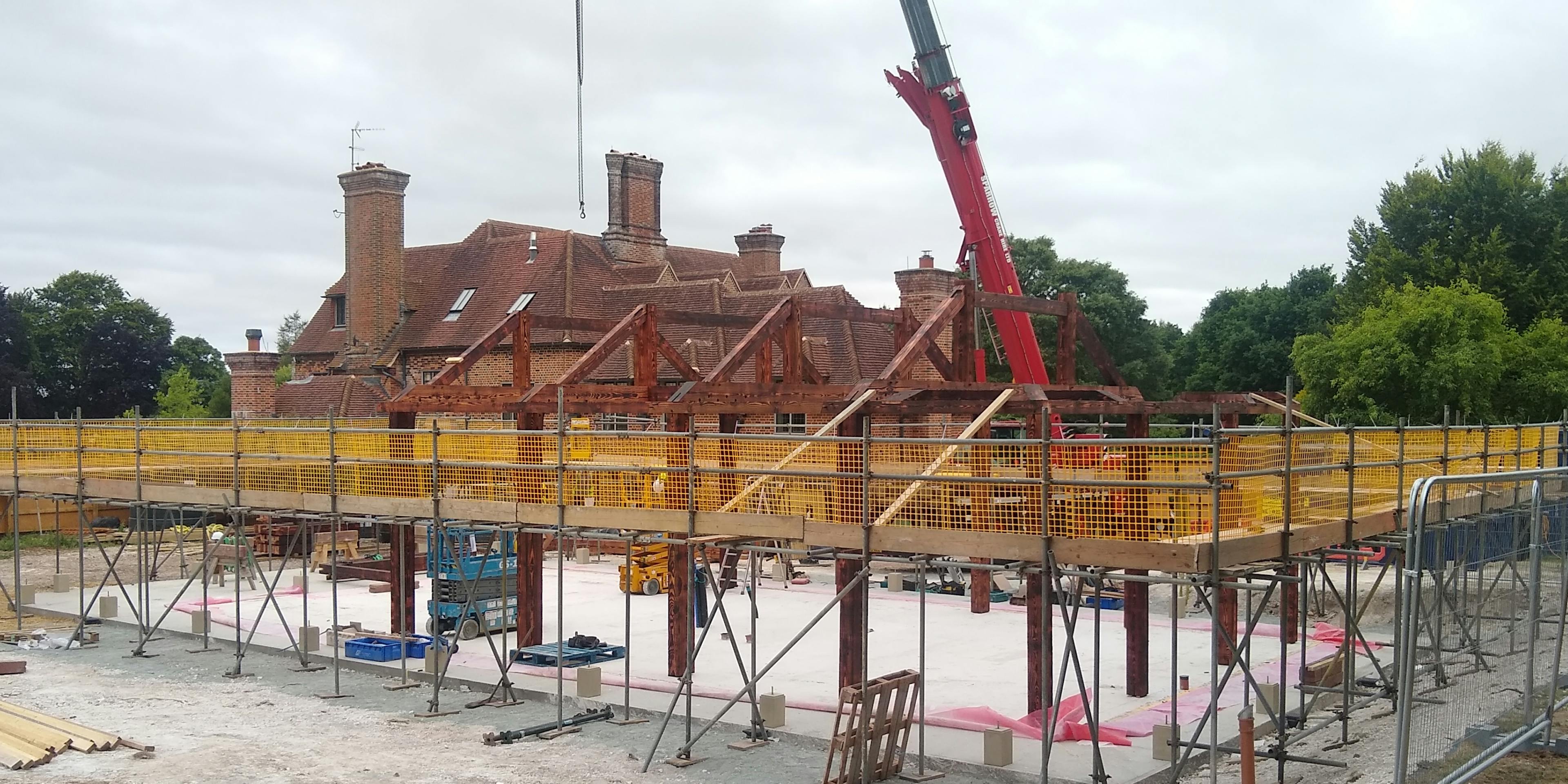 Installation of a Douglas fir framed garden annex on a construction site with a large red crane