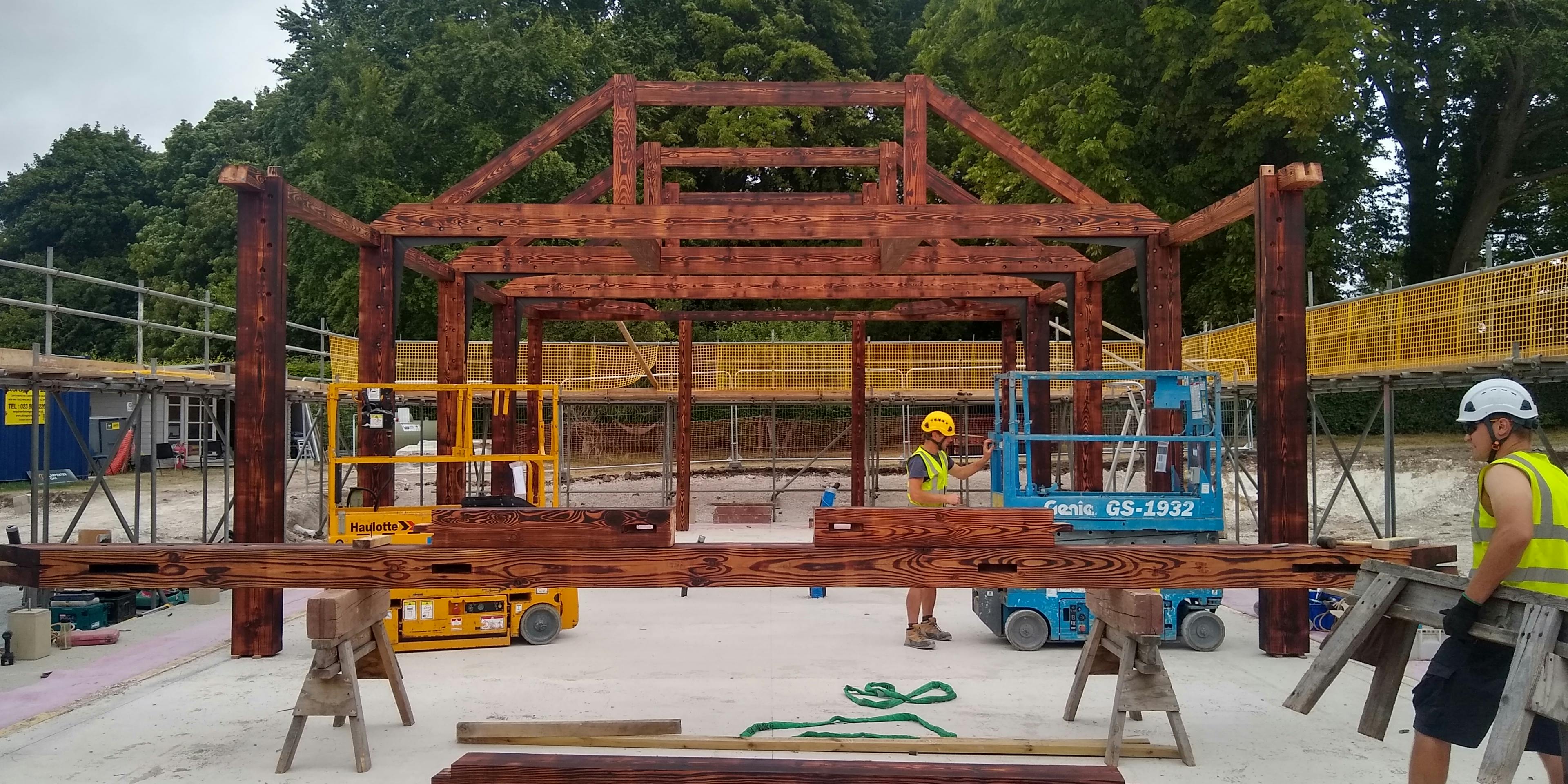 Carpenters installing a charred Douglas fir frame for a garden annex
