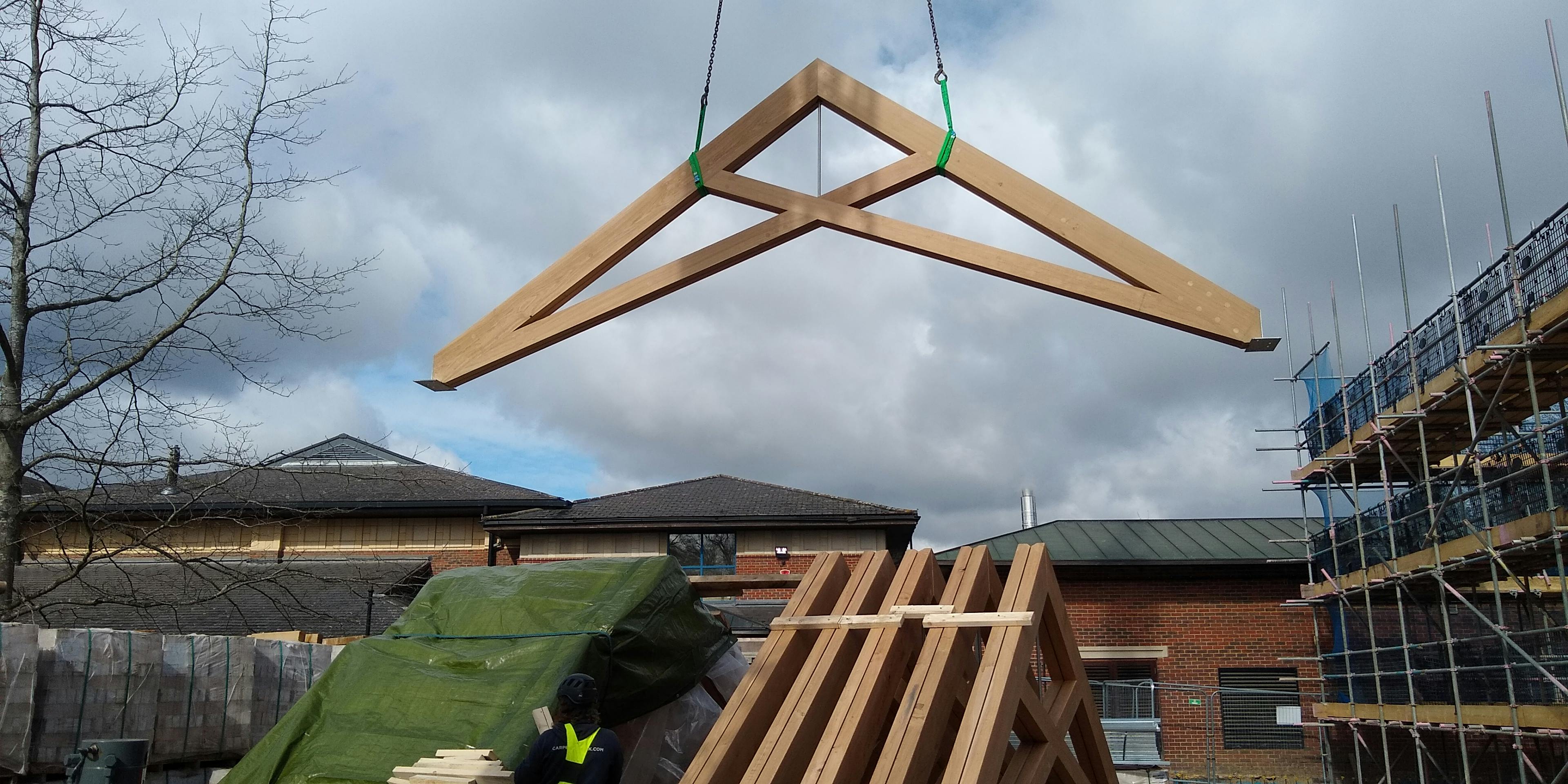 Air dried oak scissor trusses being installed with a crane for a roof in a school building