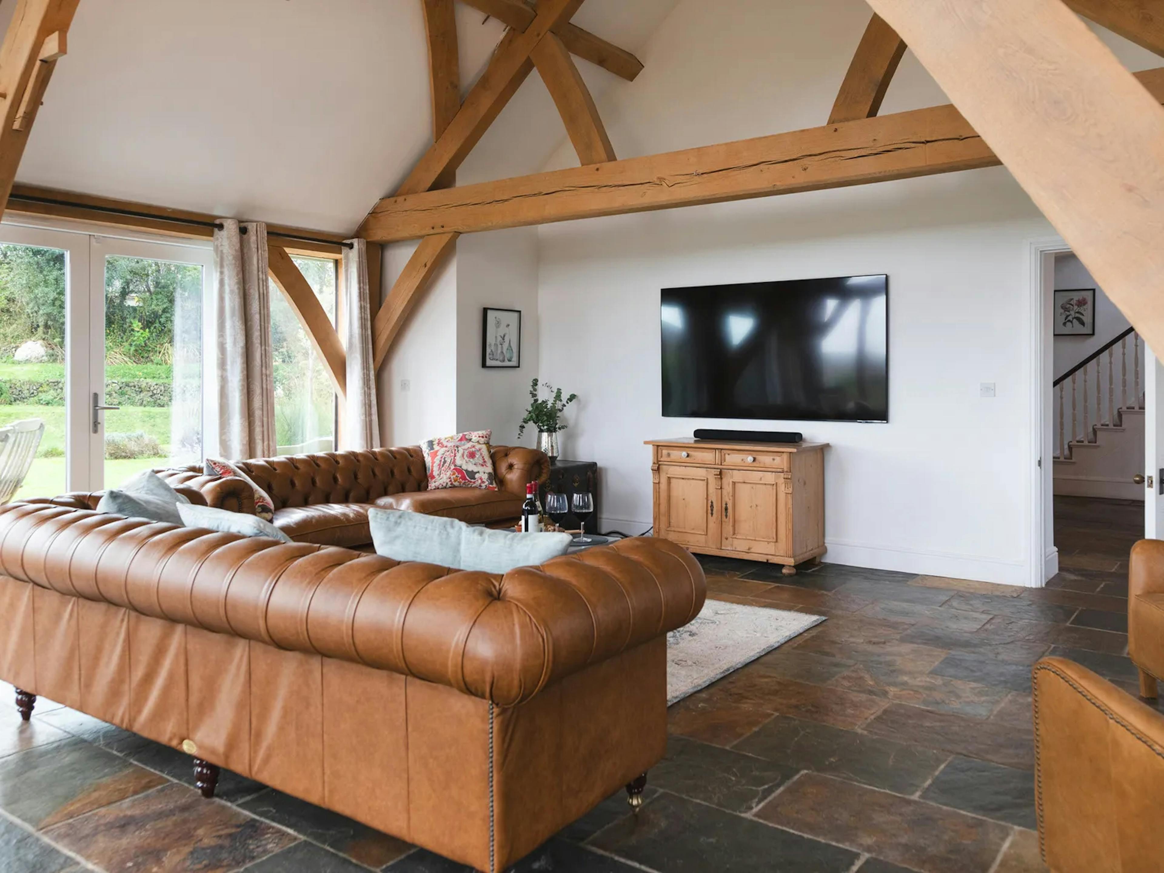 An oak framed extension with sitting area with leather sofas and a television