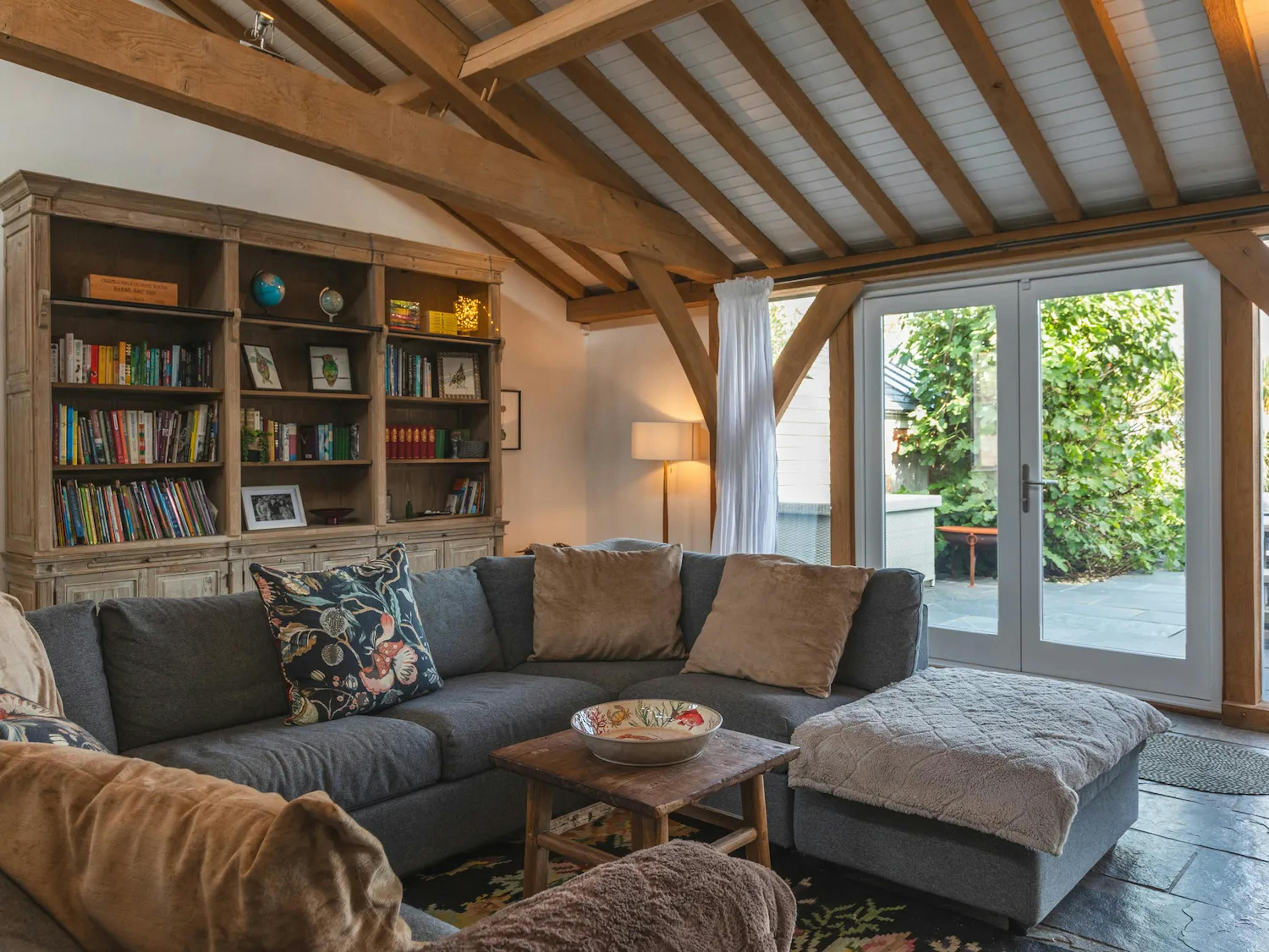 An oak framed extension with lounge and sitting area with grey sofas and French doors to a patio
