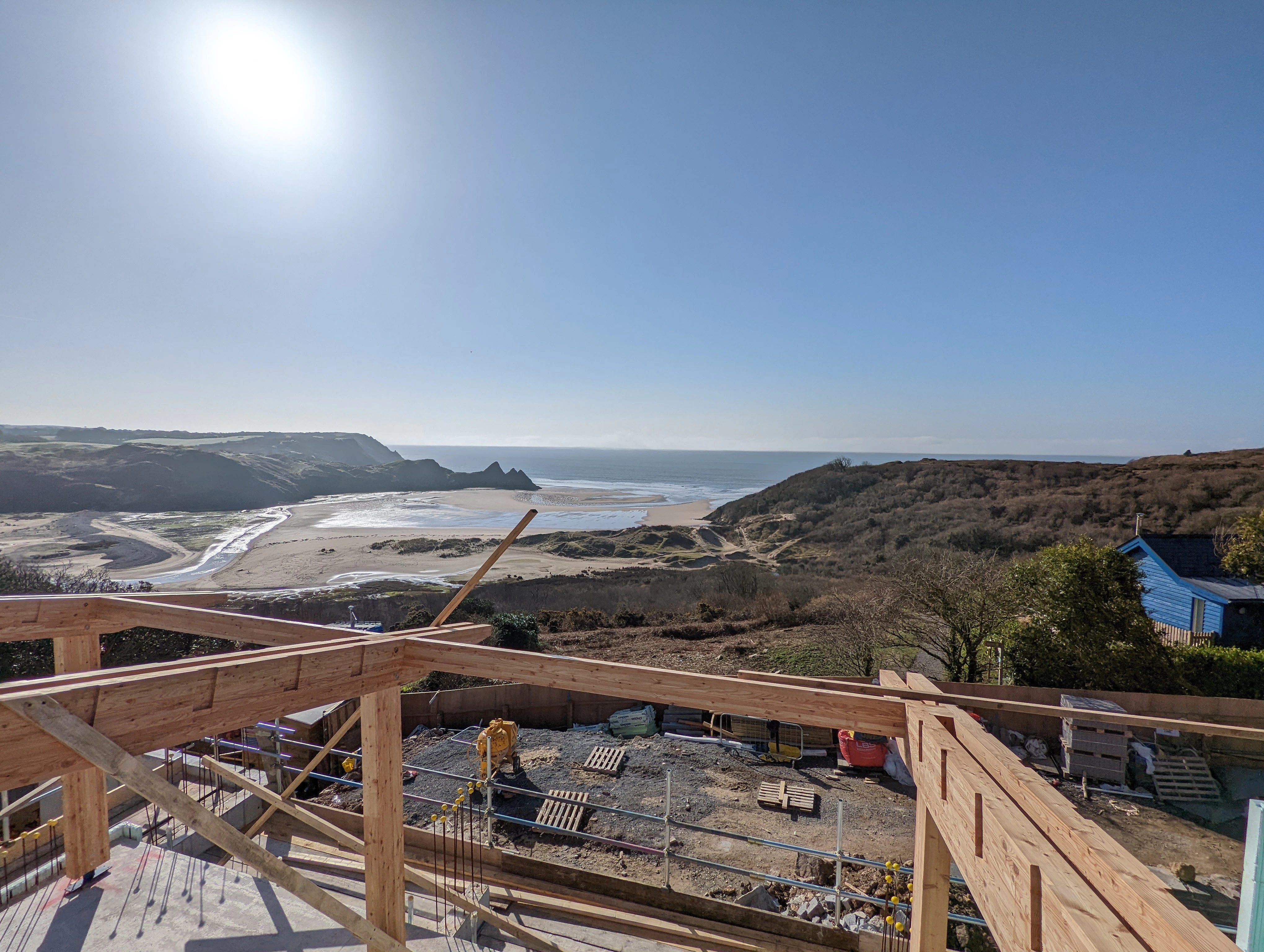A larch glulam frame being installed on a site overlooking a beach