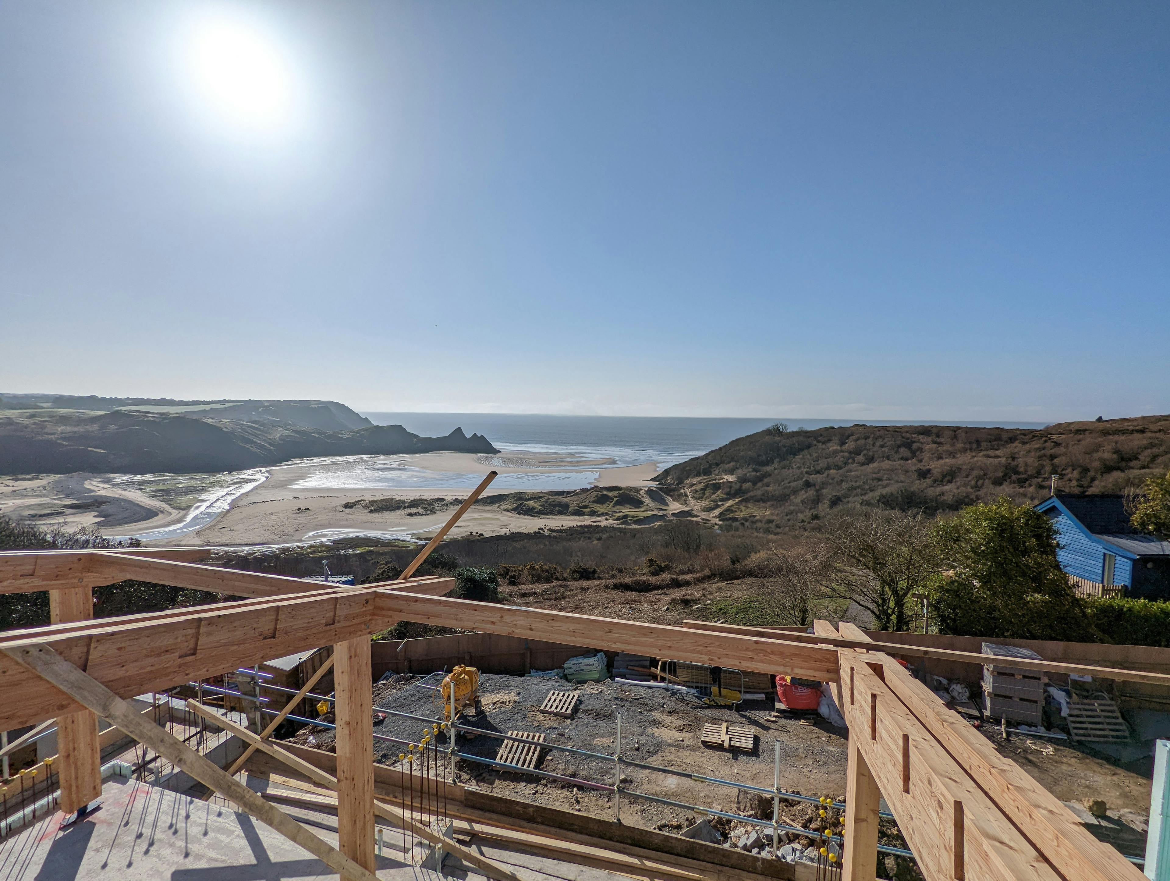 A larch glulam frame being installed on a site overlooking a beach