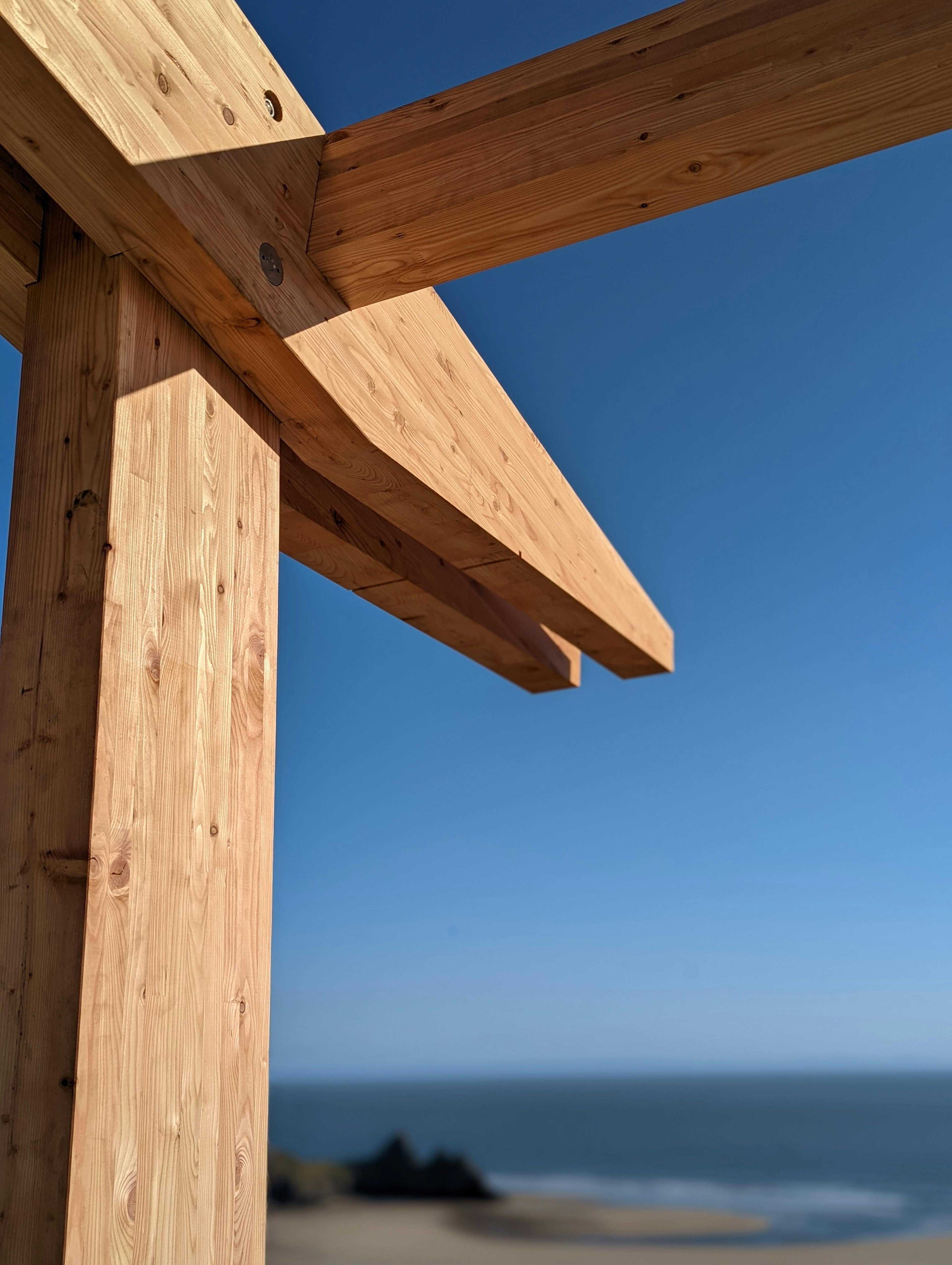 Close up of a  larch glulam frame being installed on a site overlooking a beach