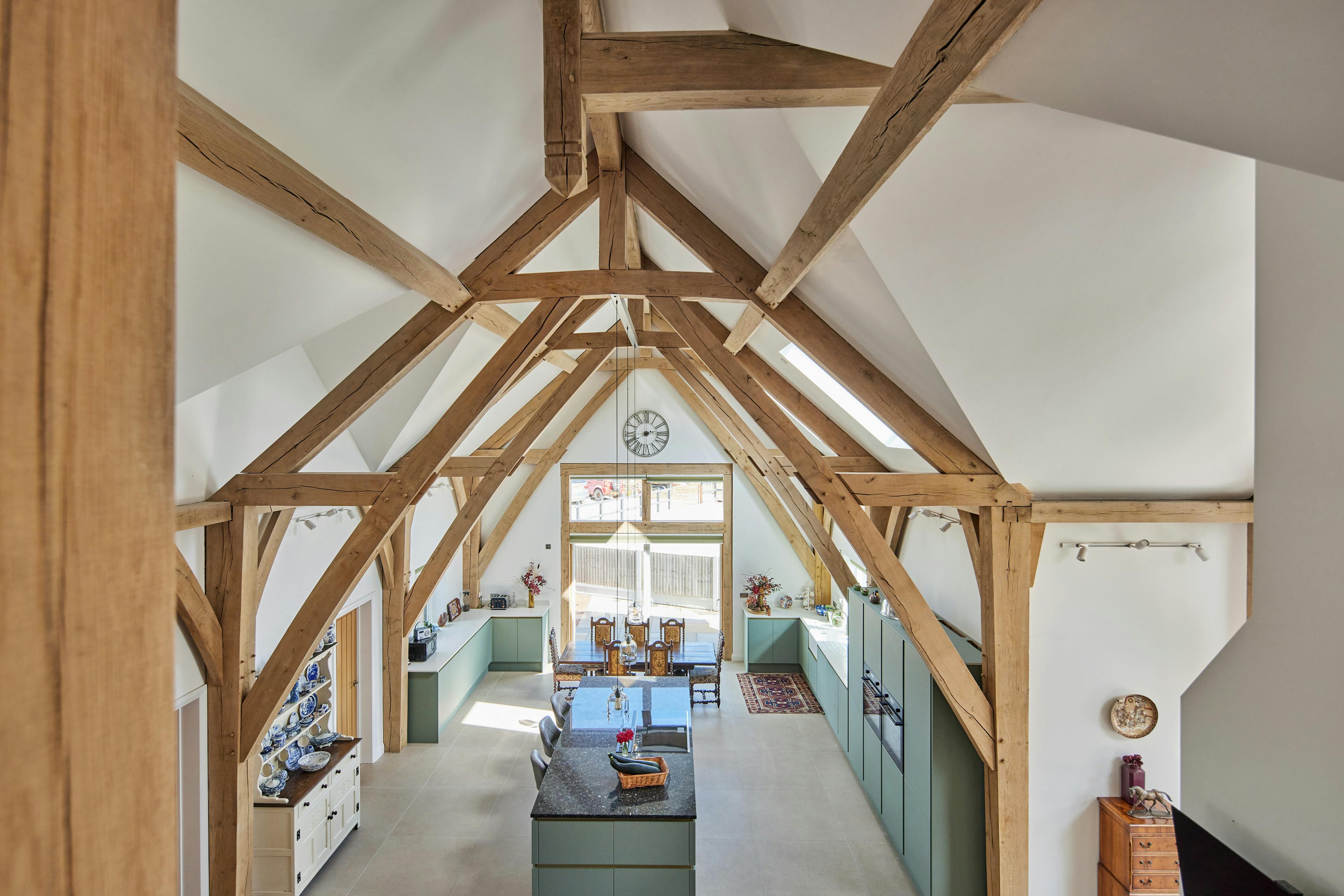 An open plan dining and kitchen area in an oak framed home with a double height vaulted ceiling, viewed from the first floor