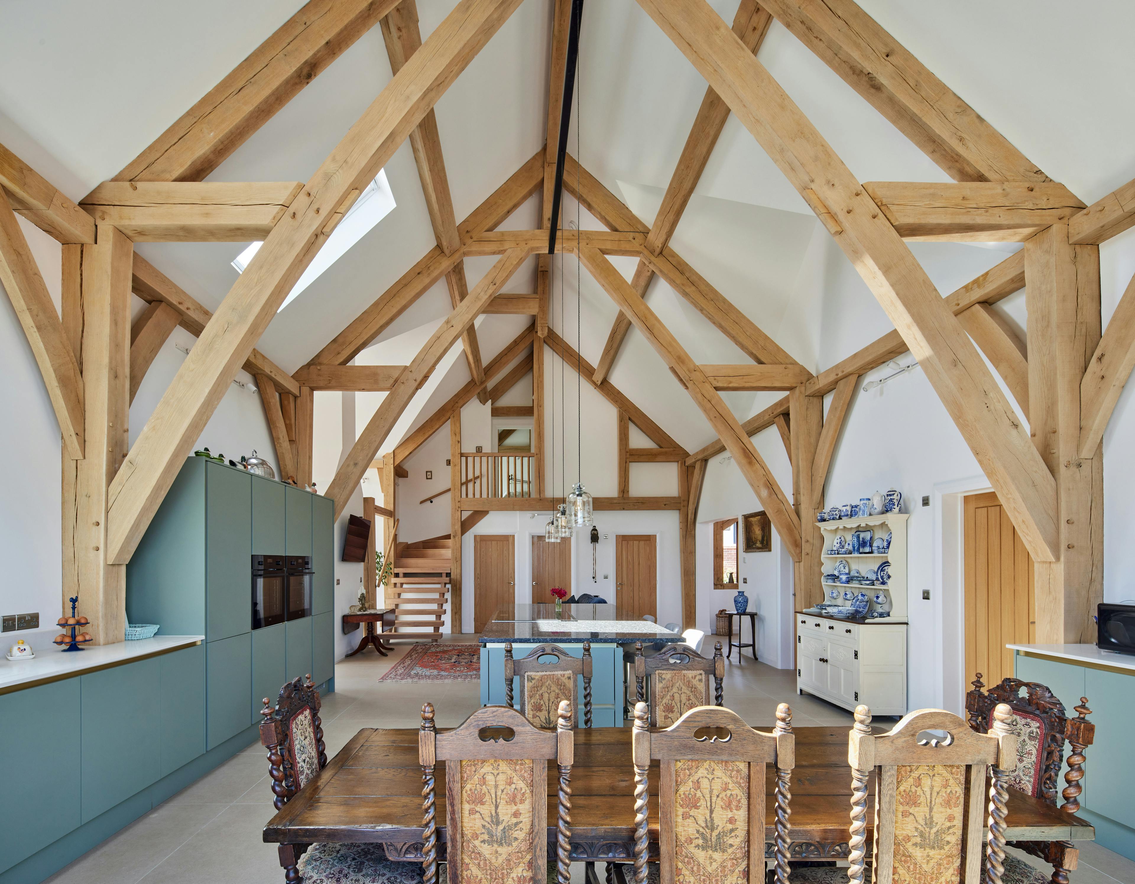 An open plan dining and kitchen area in an oak framed home with a double height vaulted ceiling