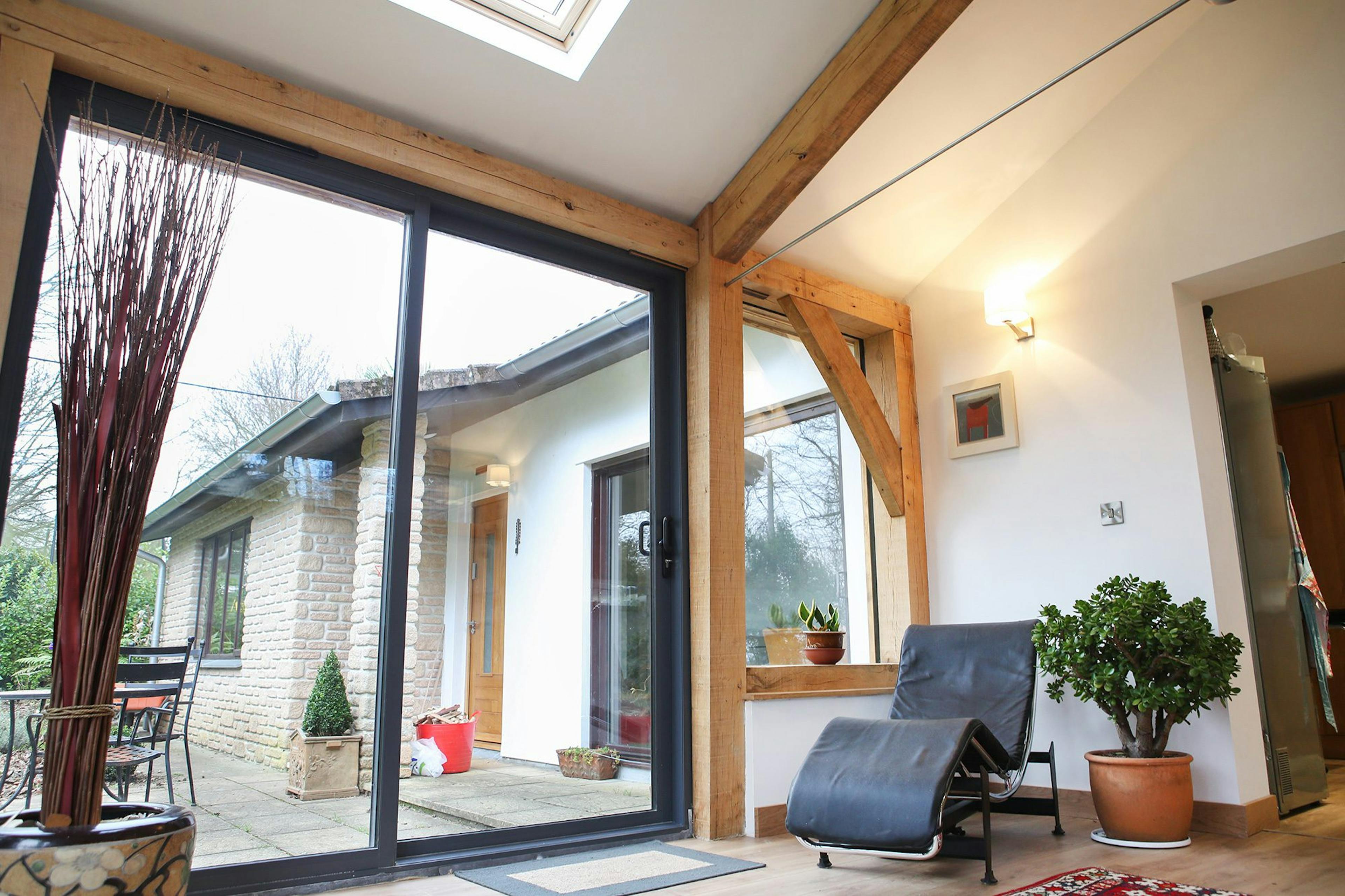 Oak-framed extension in Cornwall featuring large glass doors that open into a bright and spacious living room, blending indoor and outdoor spaces