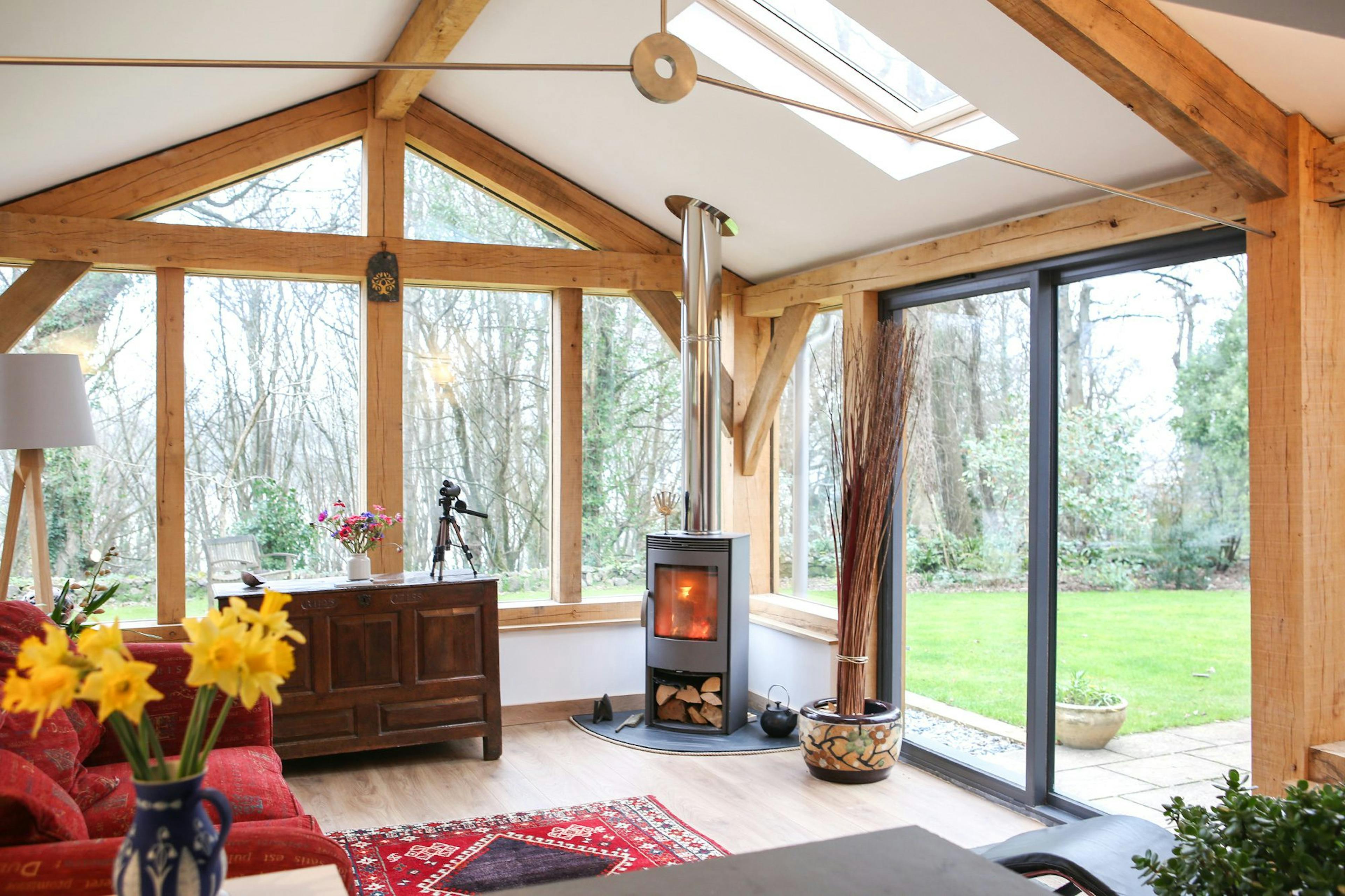 Oak-framed extension in Cornwall featuring steel accents and large glazing, creating a modern, light-filled living room with seamless indoor-outdoor connection