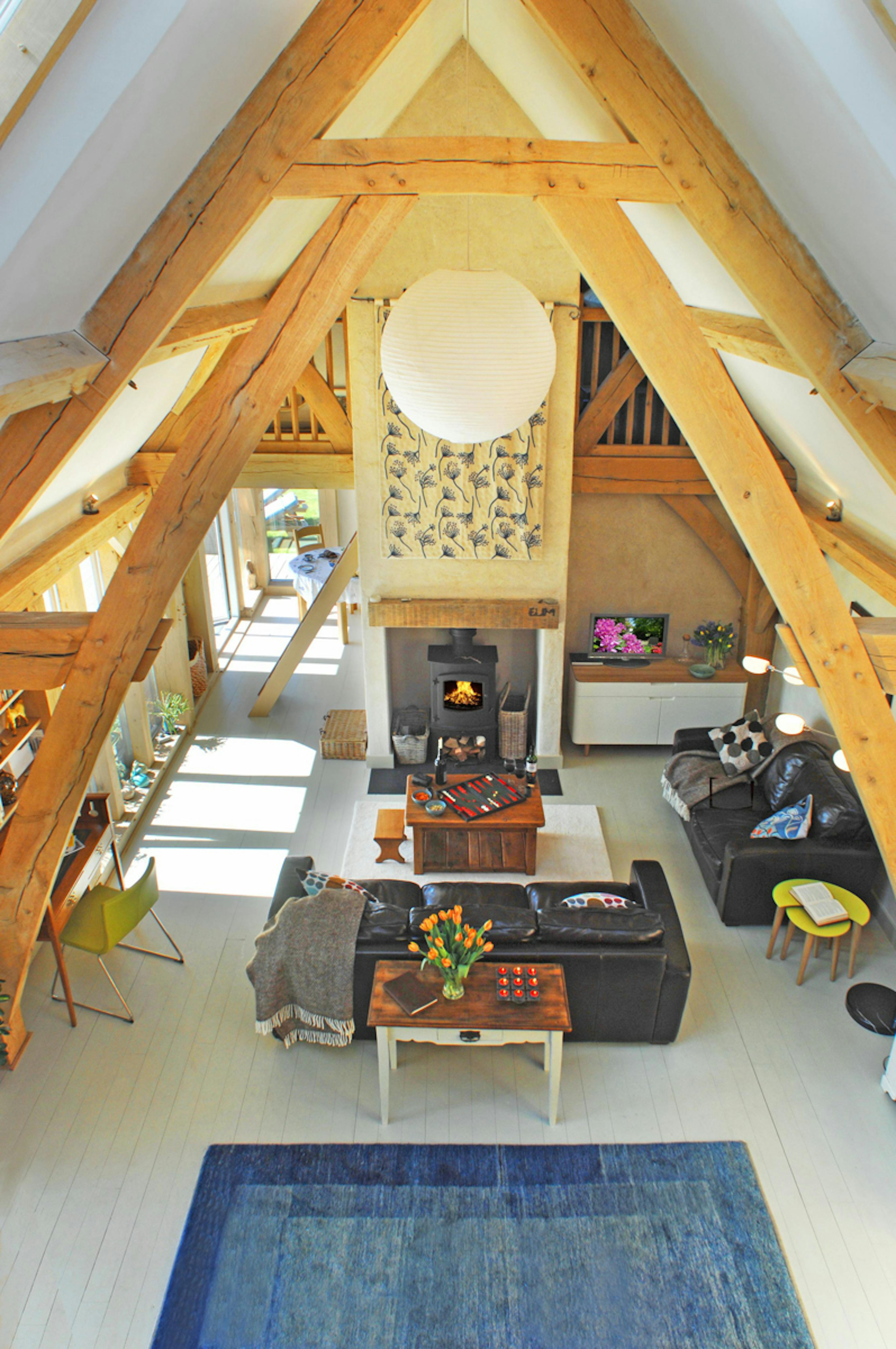 Completed interior of an oak-framed home in Cornwall, featuring a lounge with a sling brace design, vaulted ceiling, and open-plan layout, showcasing natural wood finishes and a spacious, airy atmosphere