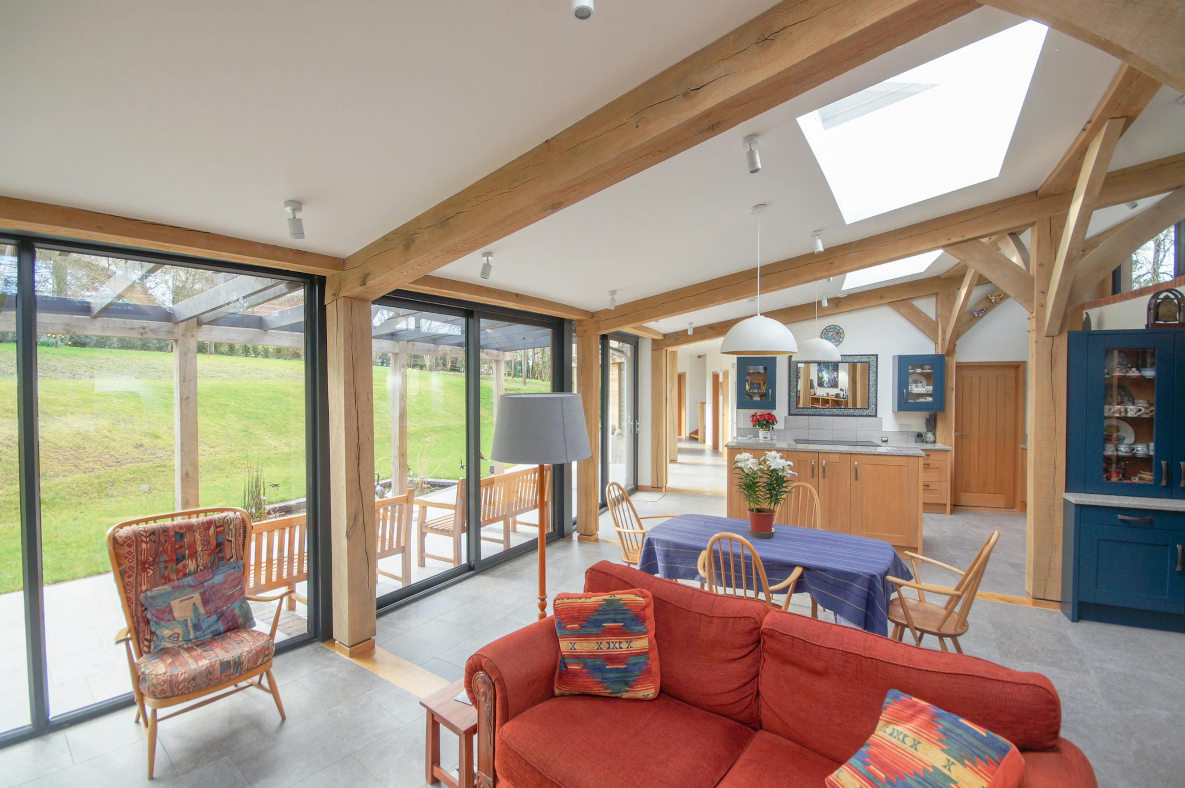 An open plan living room, kitchen, dining area in a curved oak frame home