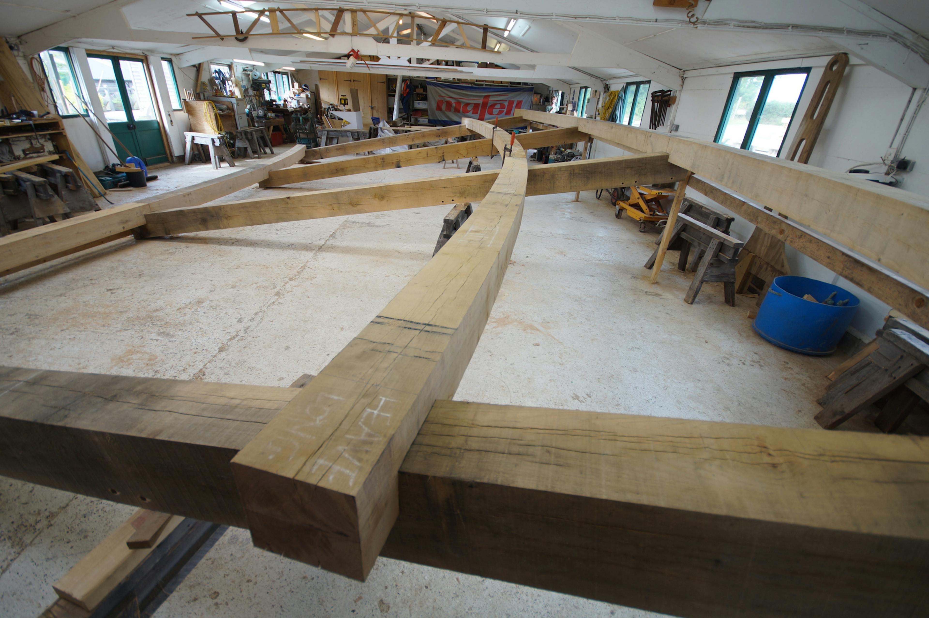 A curved oak frame during construction in a carpenters workshop