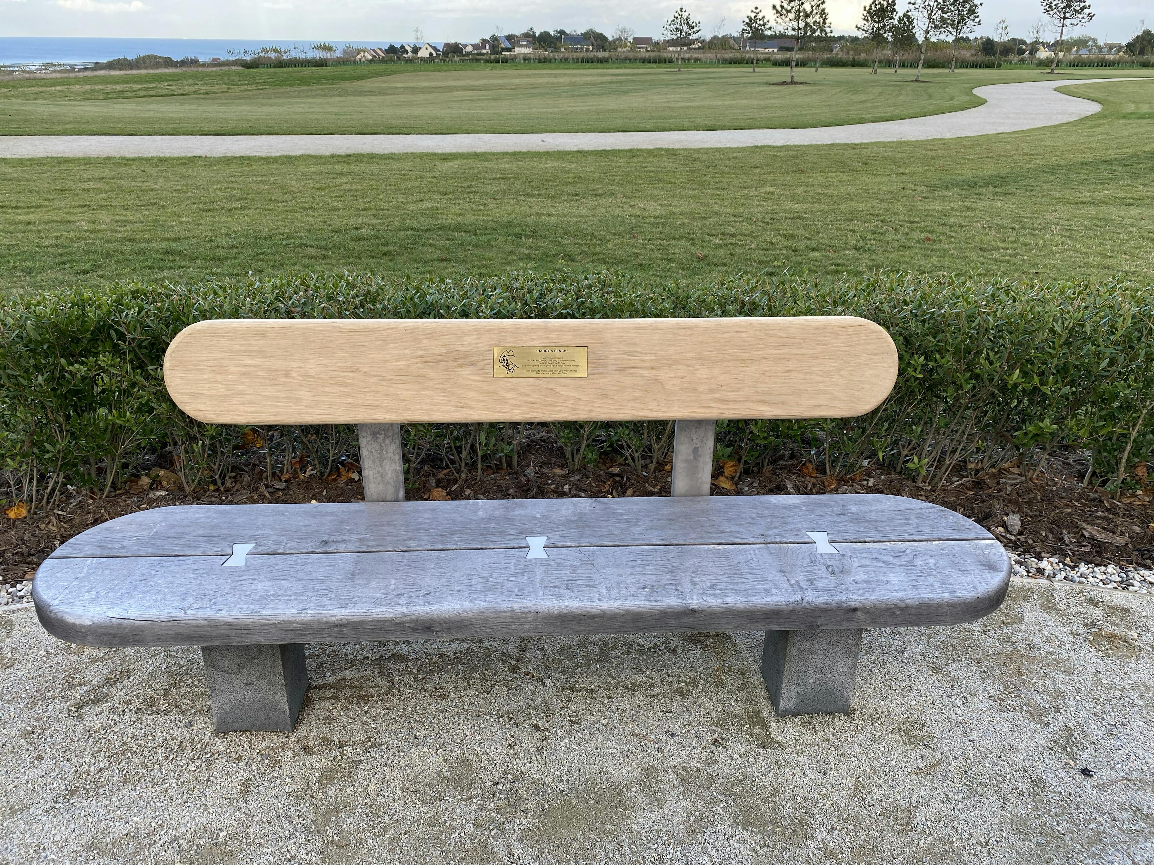 A bench with a gold plaque on a bench for veteran Harry Billinge at the British Normandy Memorial
