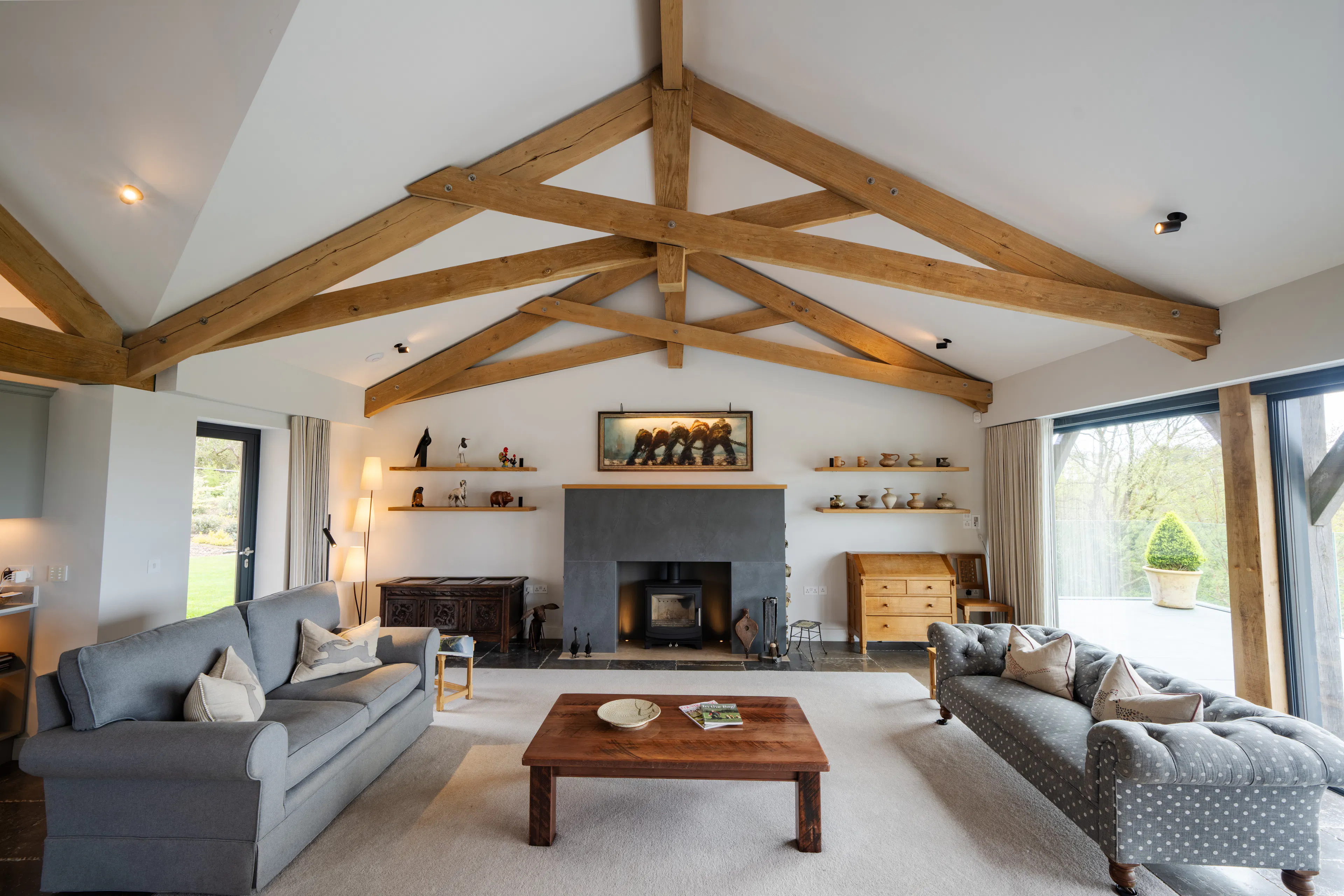 An oak framed living room with feature scissor trusses and a log burner