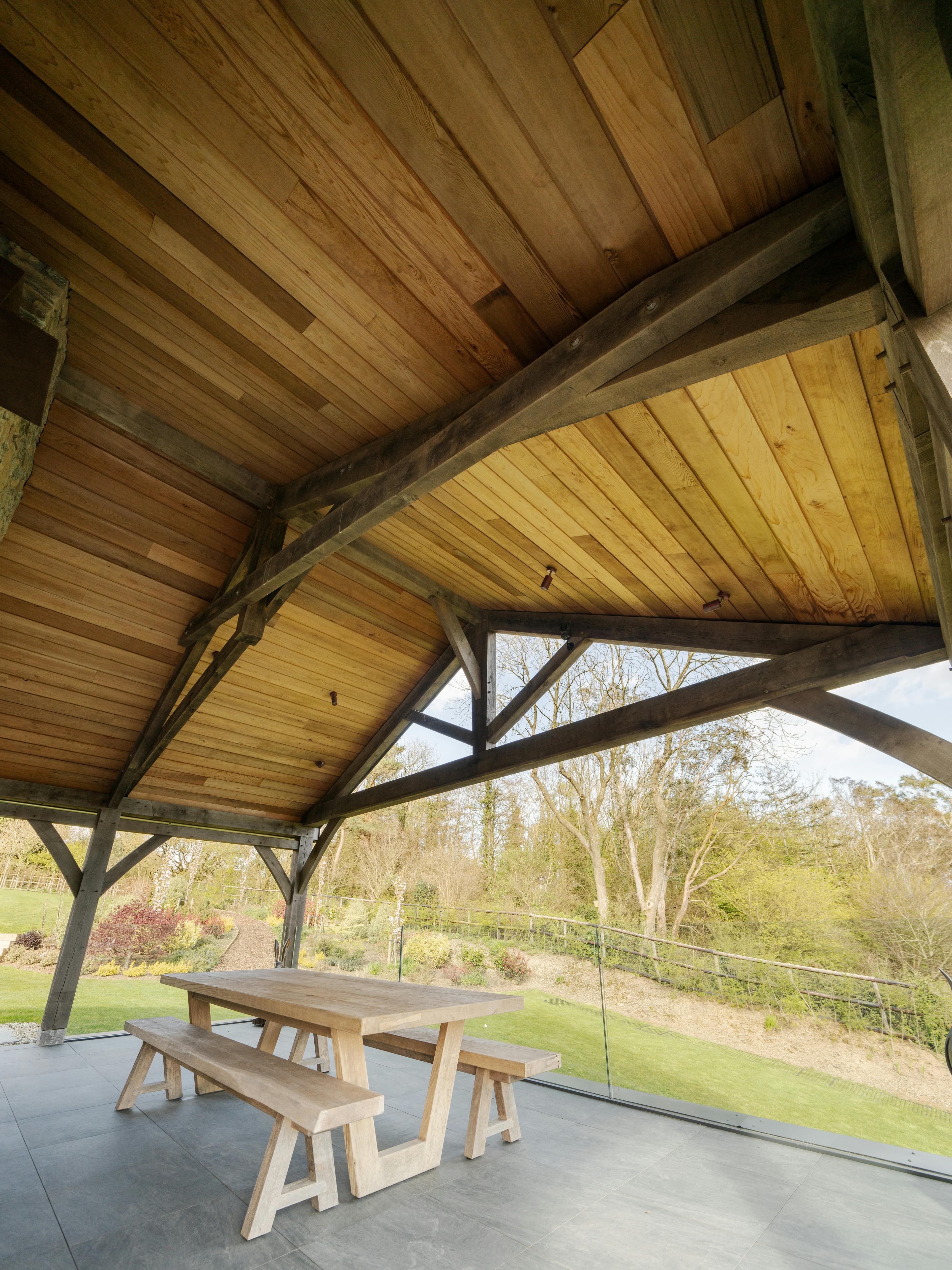 A covered outdoor eating area with an oak frame and timber cladding in the ceiling