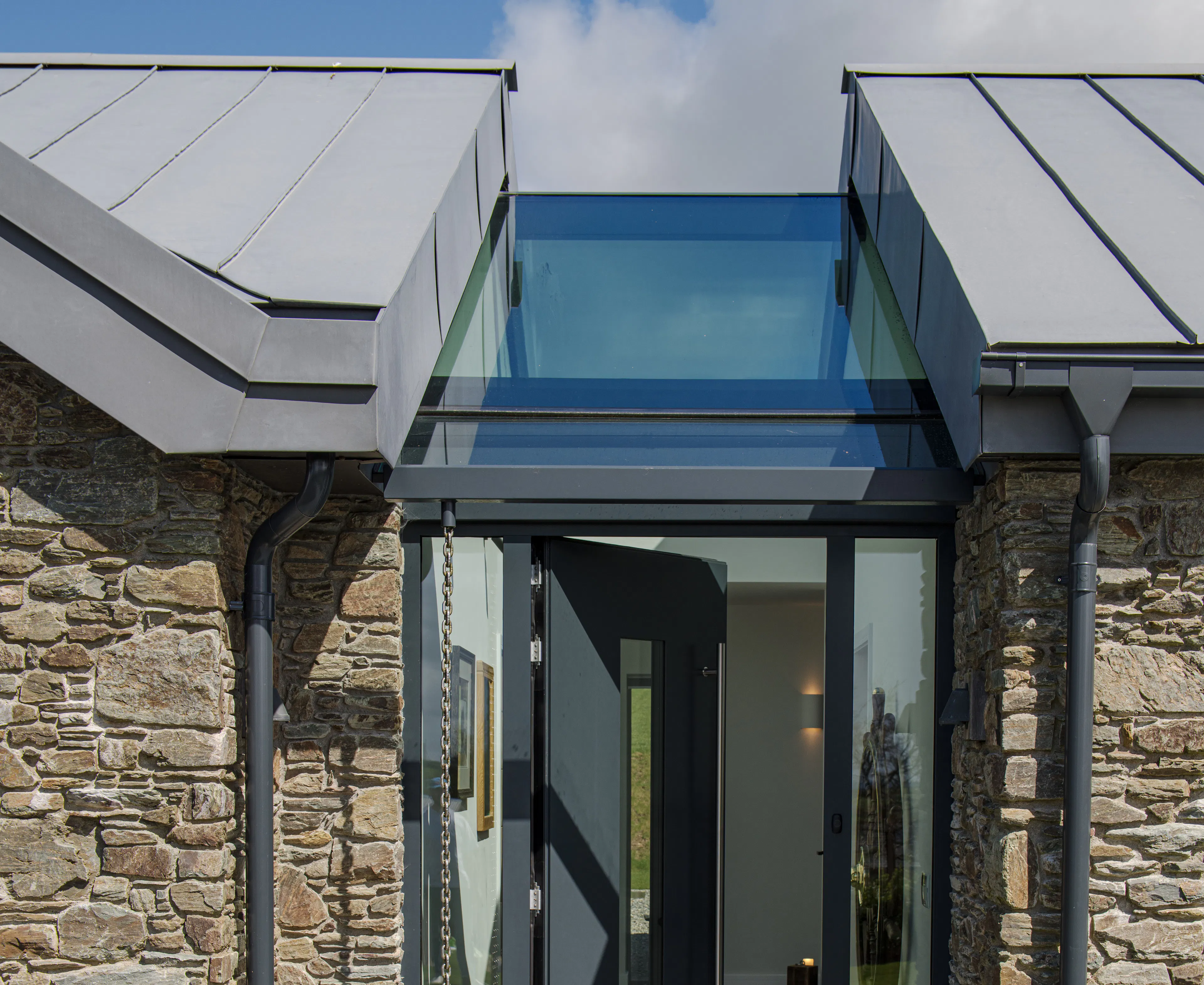 An entrance way with a skylight of a stone clad oak framed home with a zinc roof