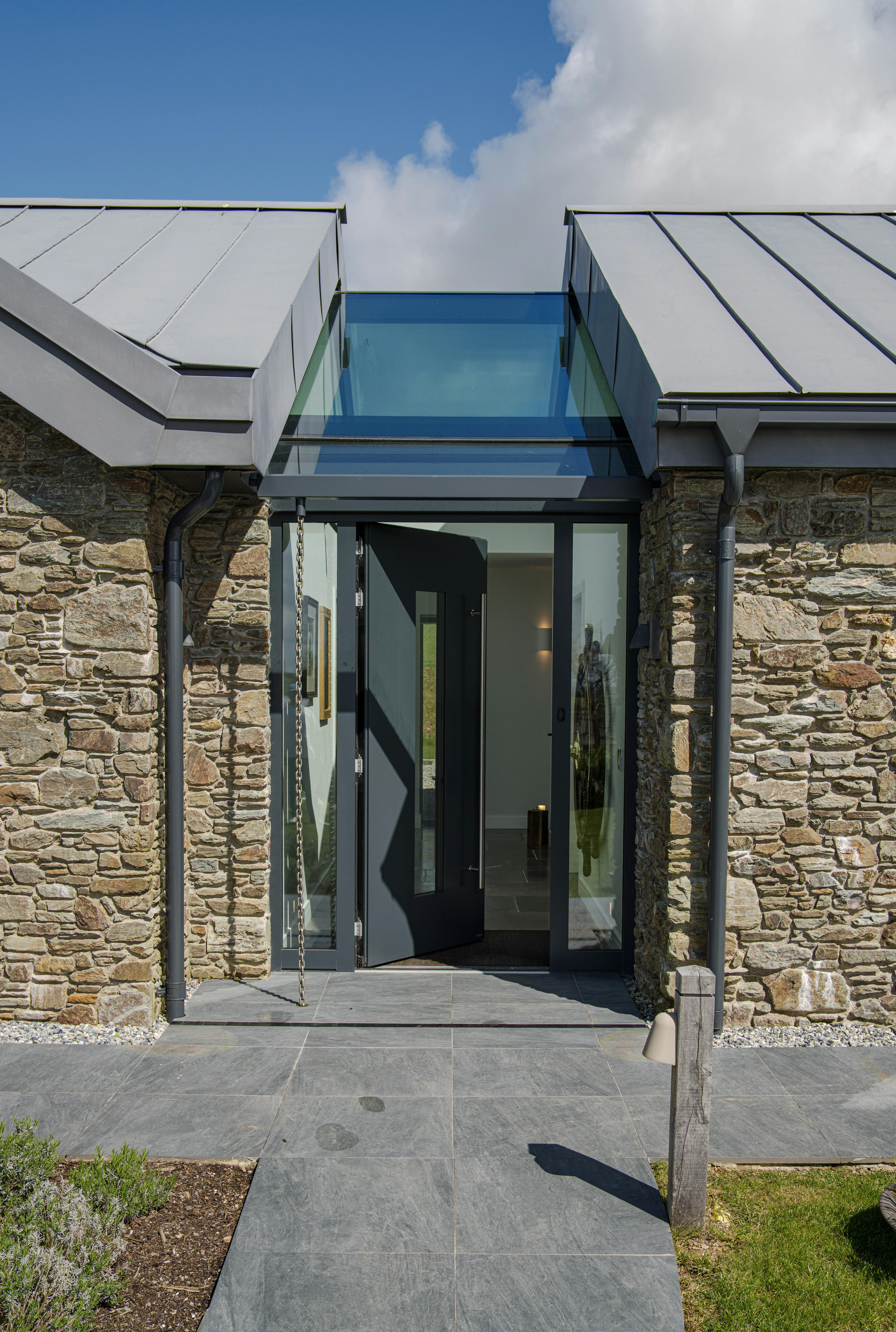 An entrance way with a skylight of a stone clad oak framed home with a zinc roof