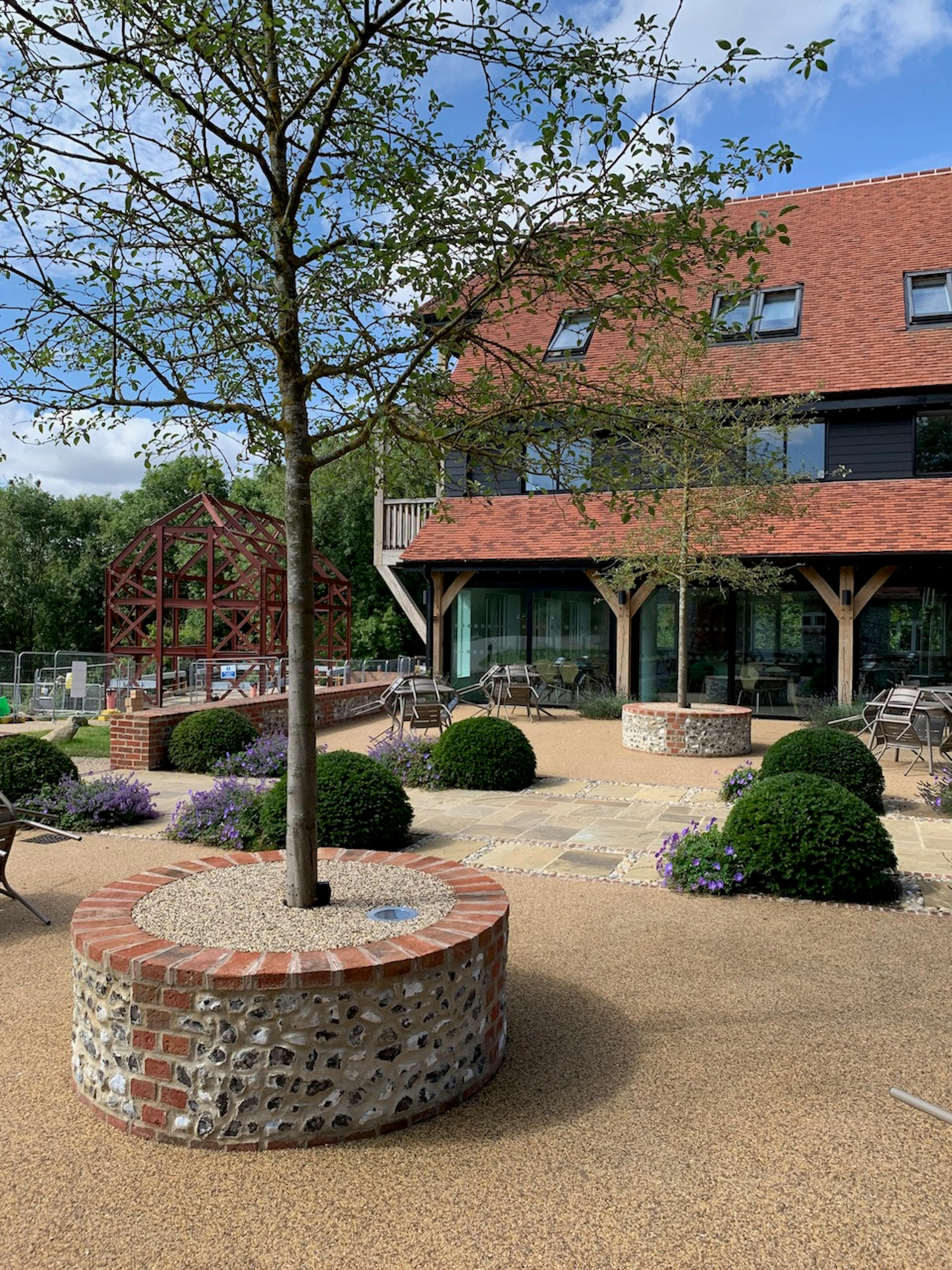 A courtyard with oak posts on a large red roofed building