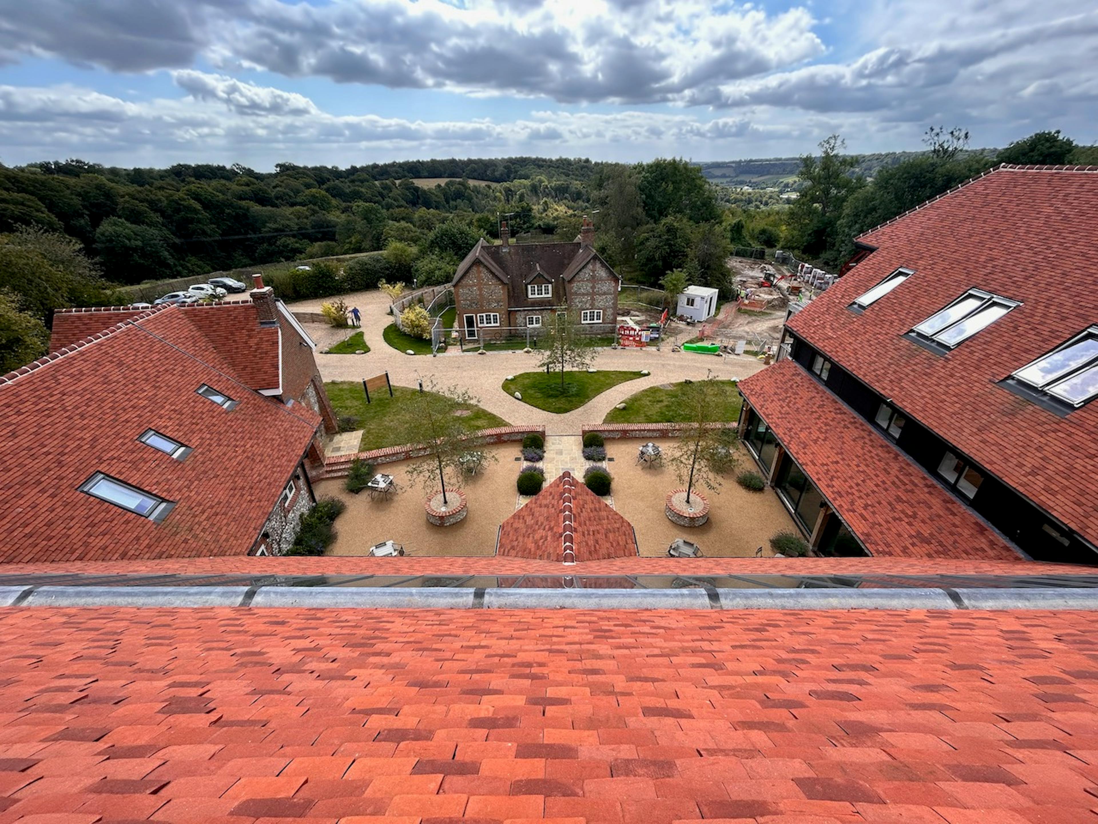 A courtyard below a large red roofed building, taken from the roof