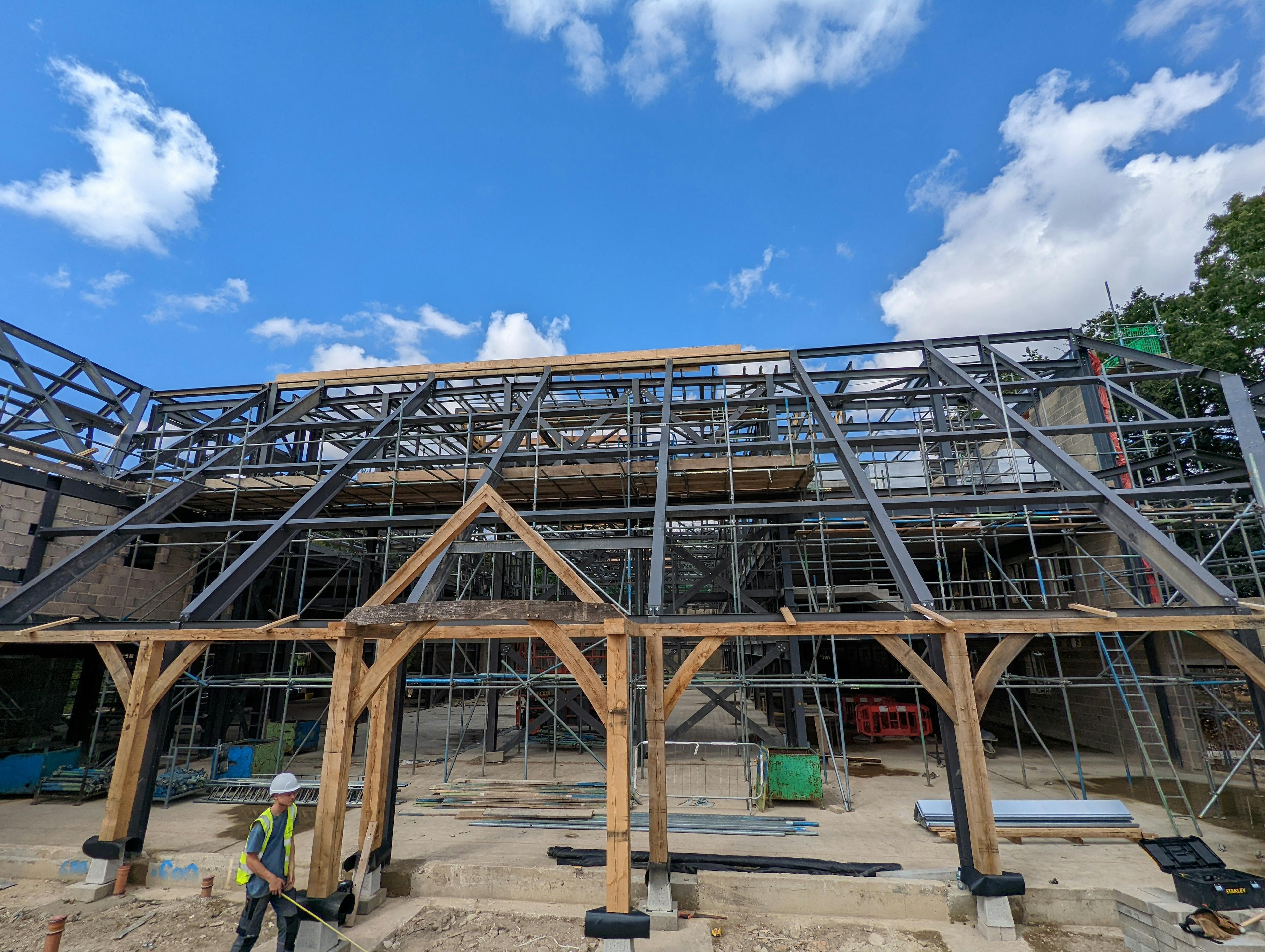 A large steel frame for a building with an oak veranda and porch being during construction