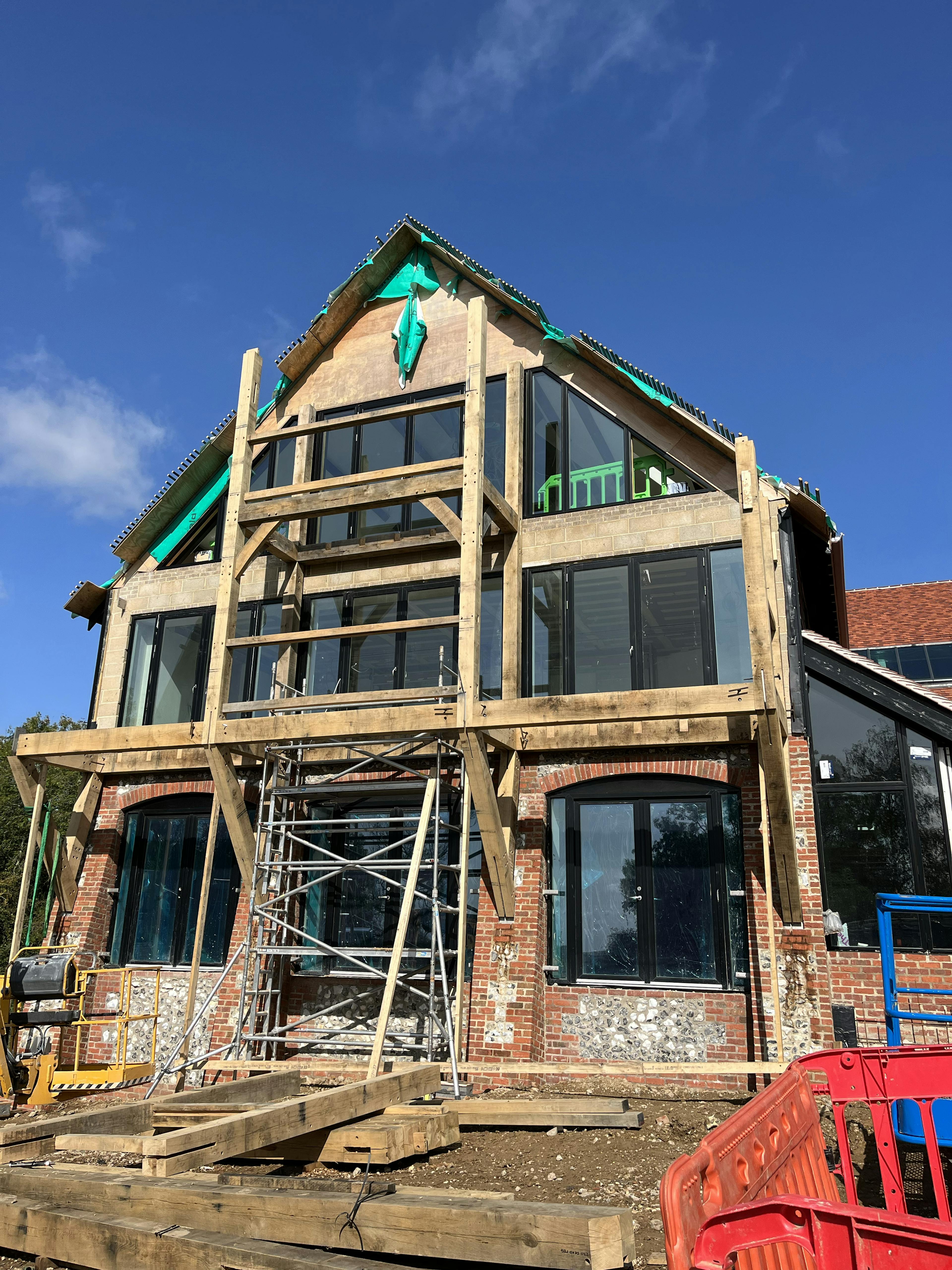 The end of a large building during construction with an oak balcony being added
