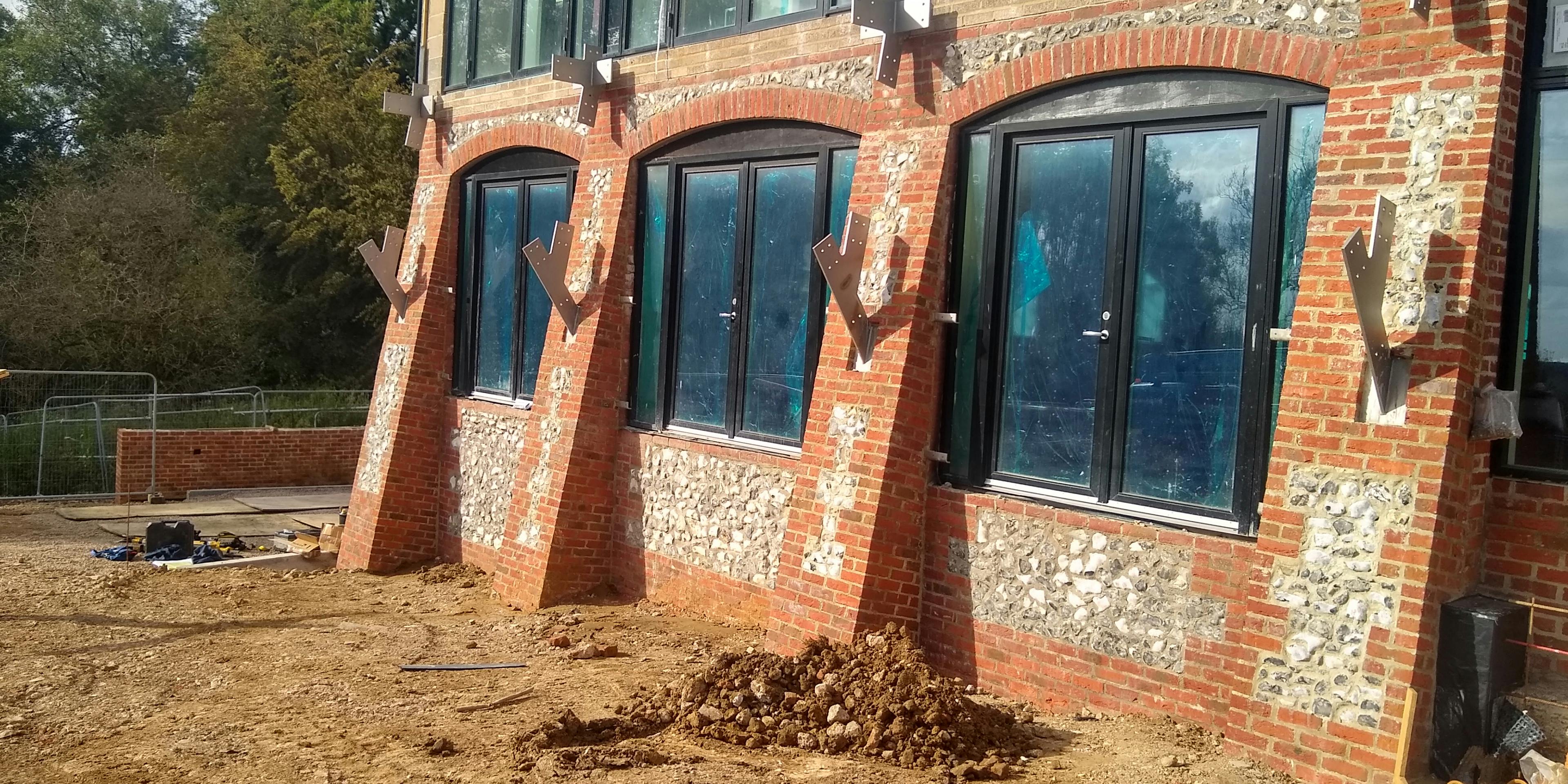 A construction site with a building with brick and flint walls