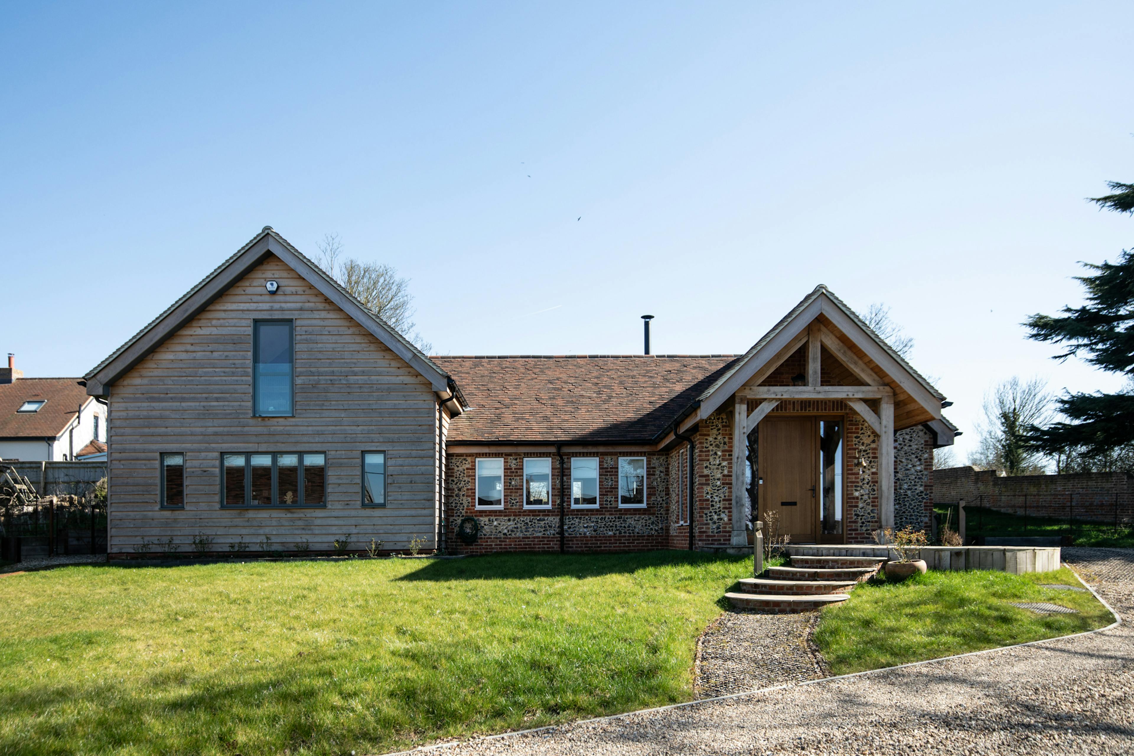 Exterior image of an oak framed house with a large oak porch and timber cladding
