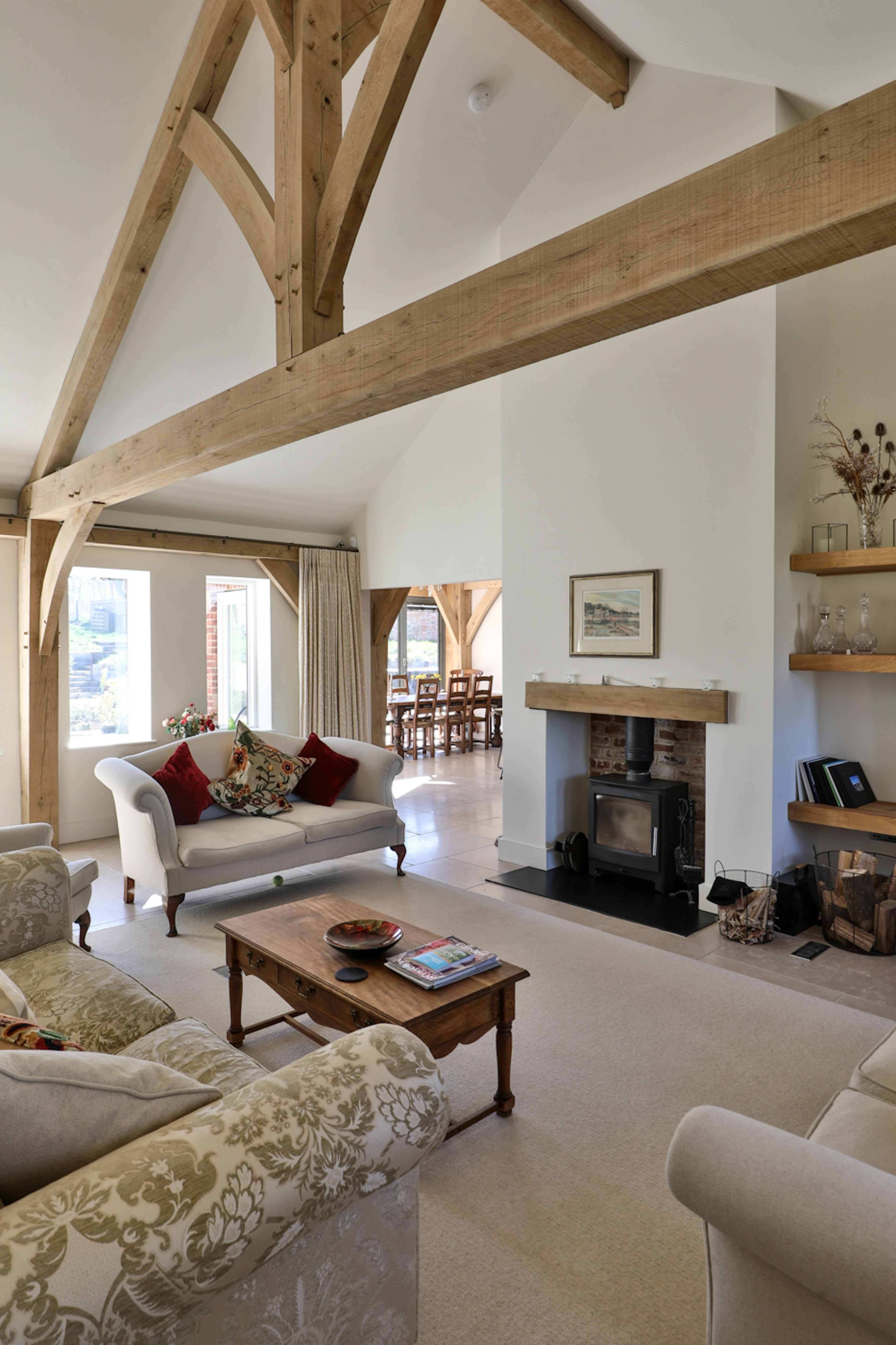 An oak framed lounge with a large truss, comfortable sofas and a log burner