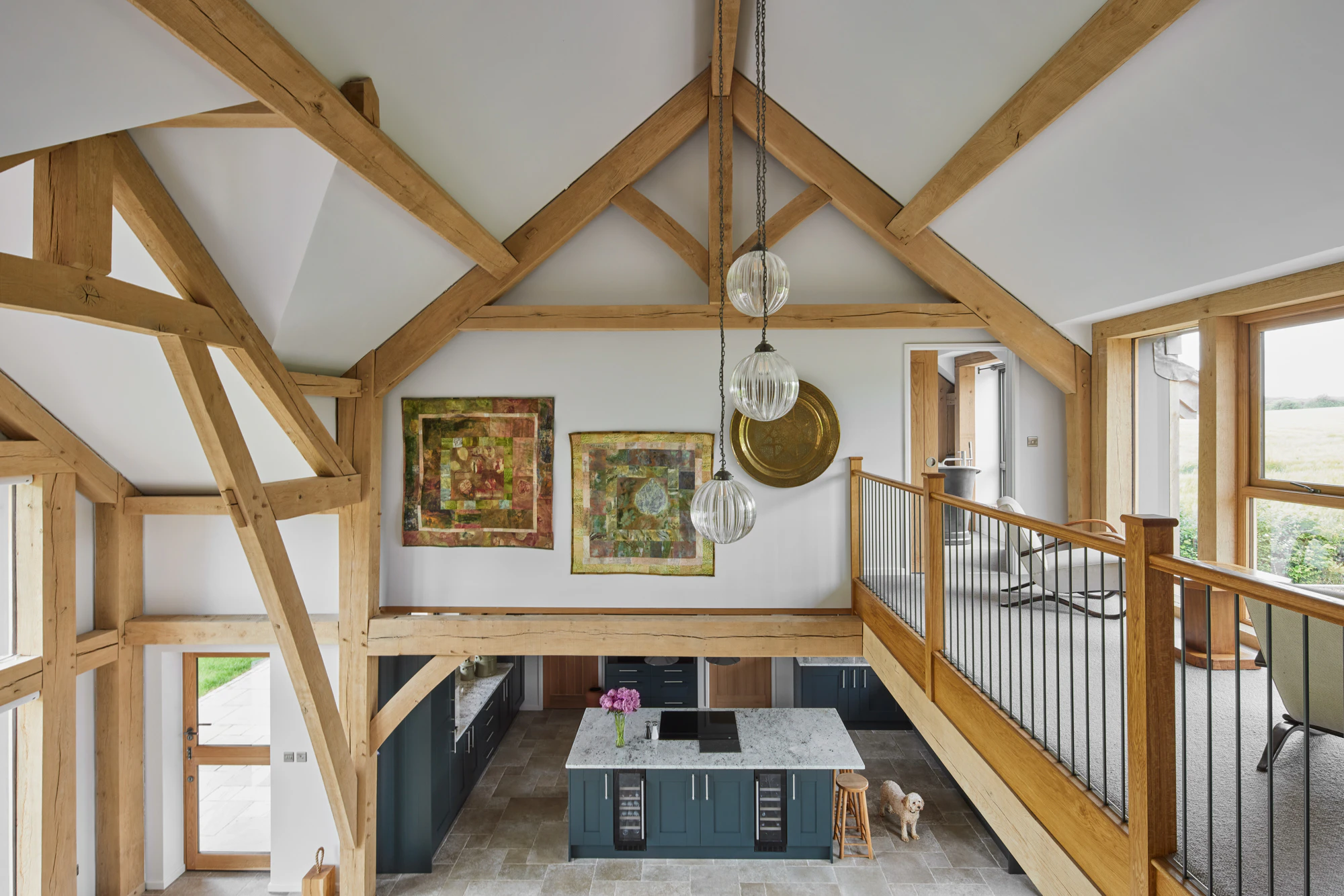 A large open plan living, dining and kitchen space with vaulted ceilings and a mezzanine landing area in a large oak framed home