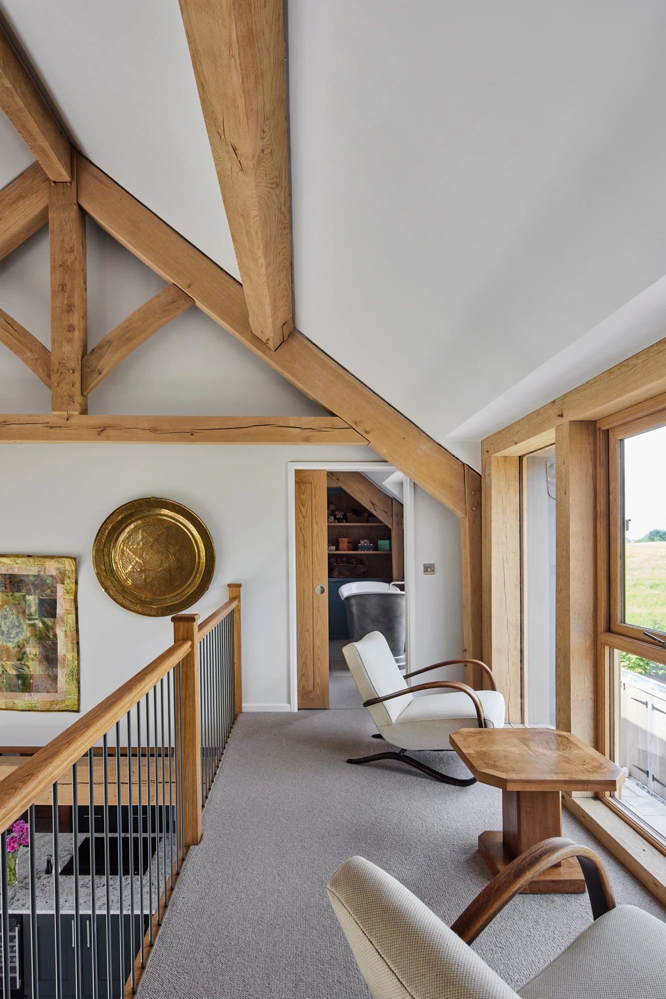 A mezzanine landing area with armchairs in a large oak framed home