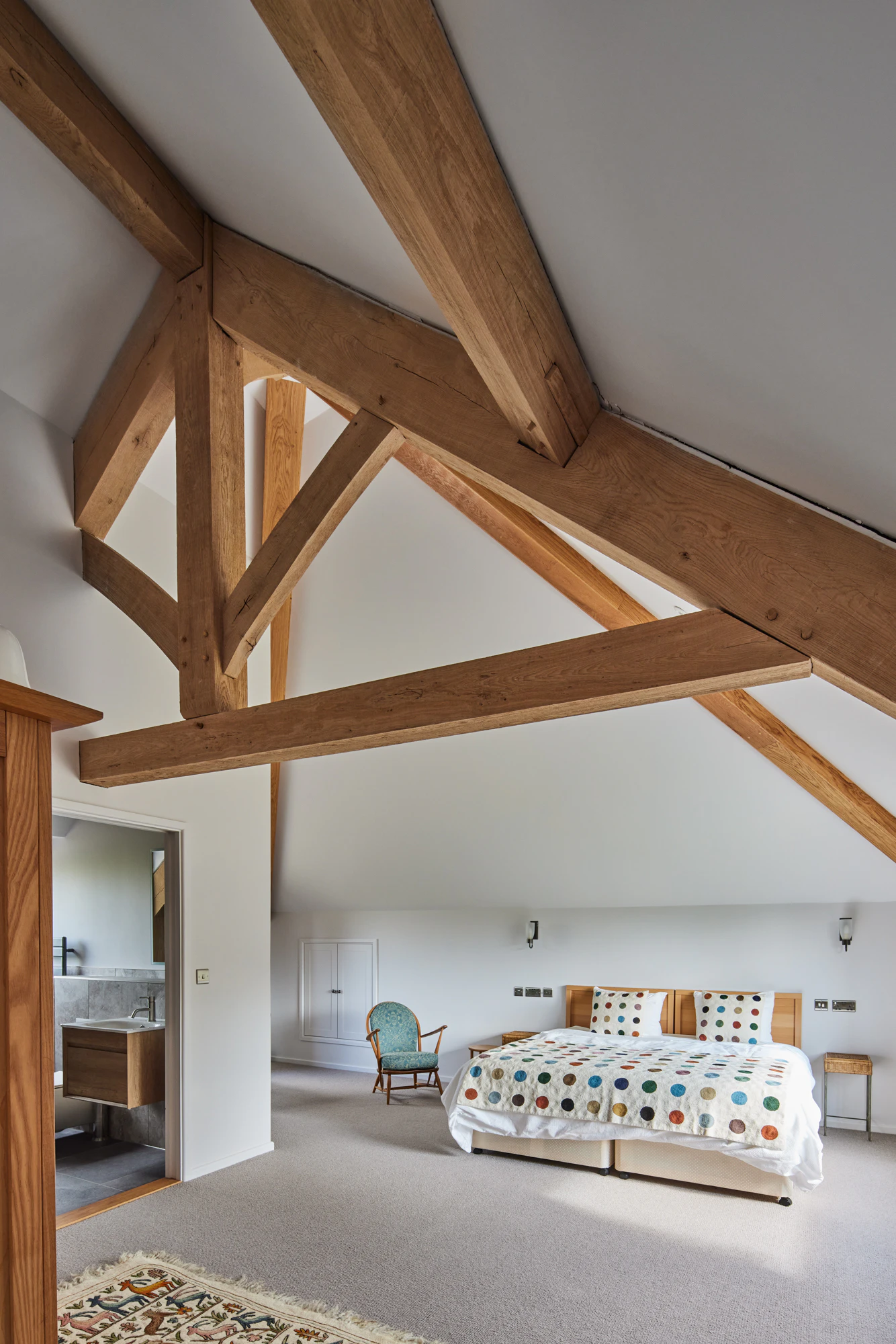 A bedroom with a vaulted ceiling in a large oak framed home