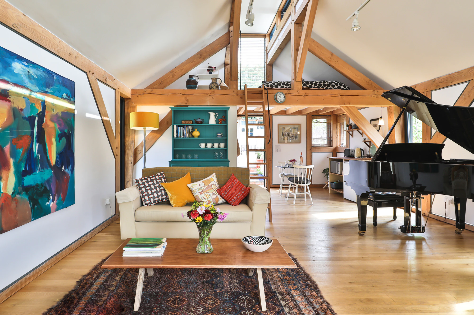 Sofas, a wooden coffee table and a black grand piano in an open plan Douglas fir framed living room