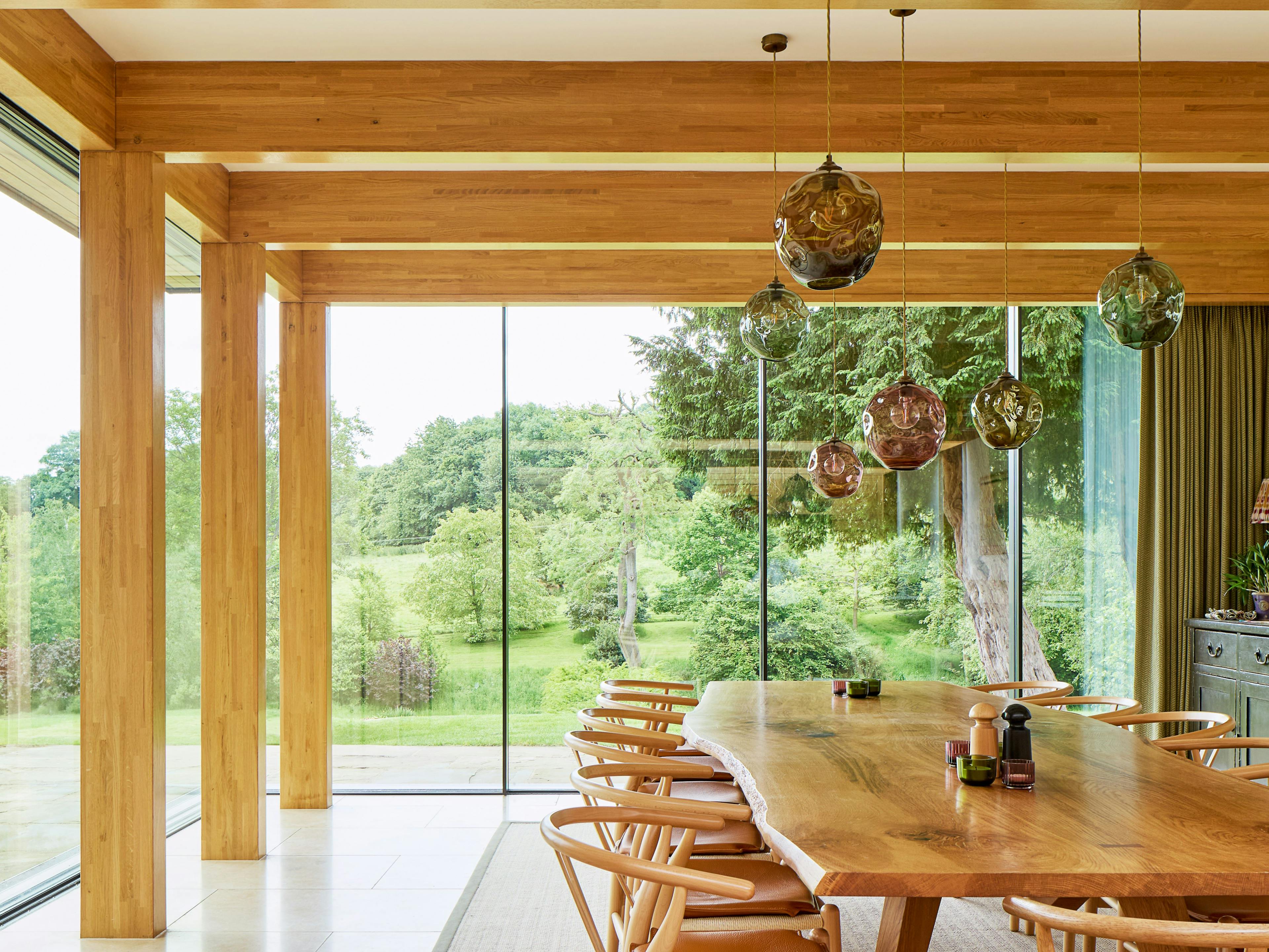 An oak glulam framed dining area with glazed windows and views into a garden