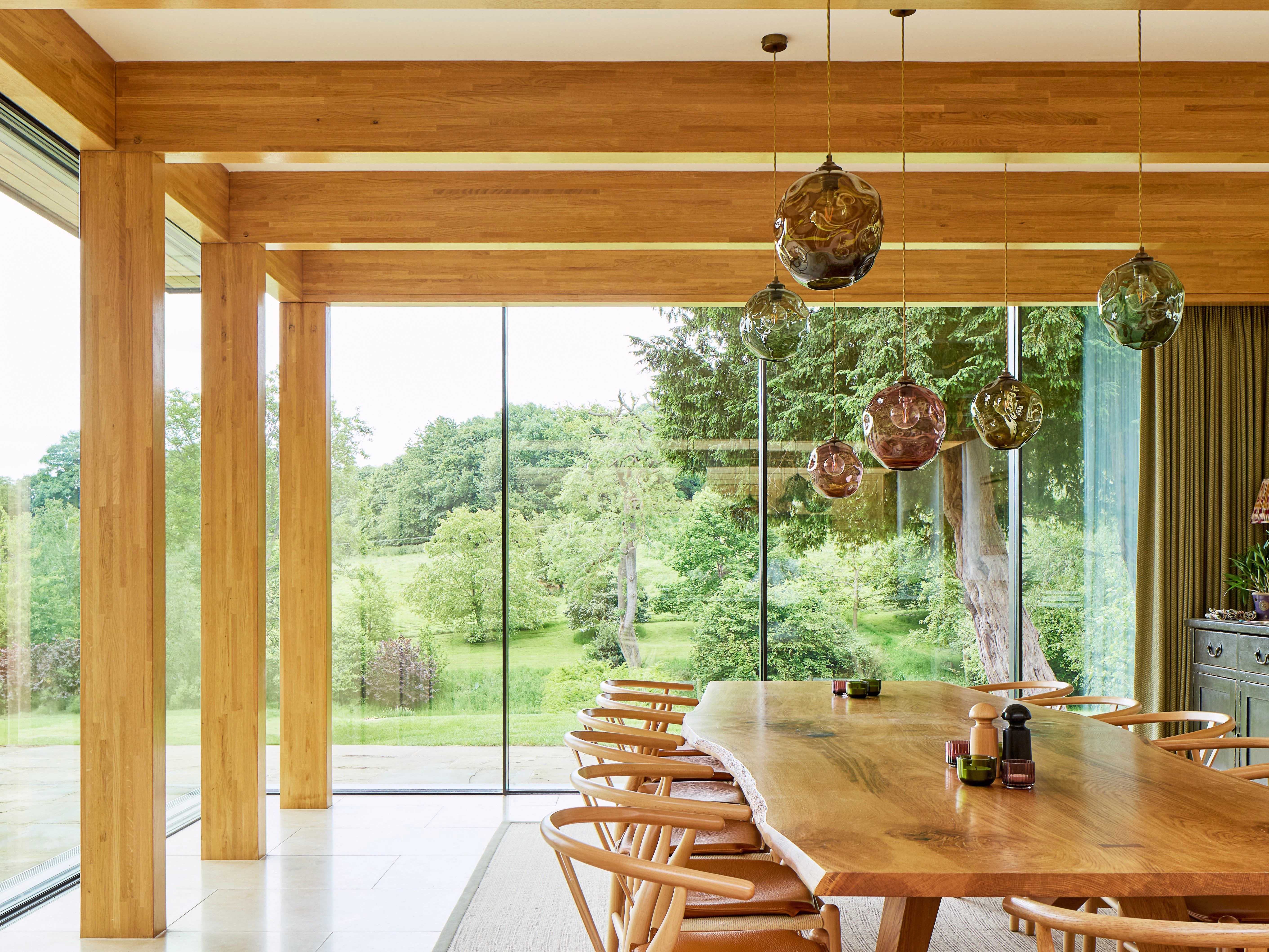 An oak glulam framed dining area with glazed windows and views into a garden