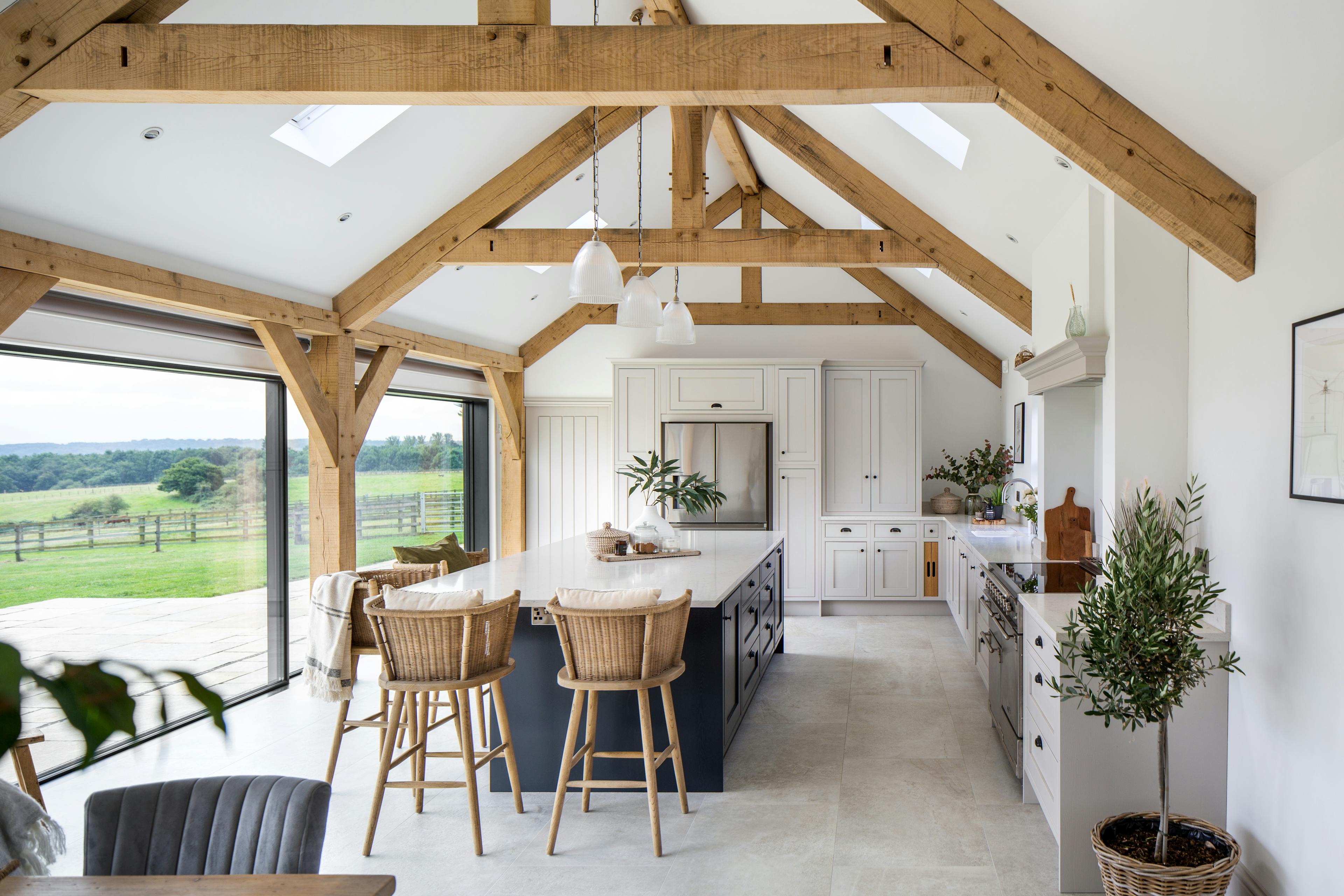 Interior view of a partially oak-framed open-plan kitchen with large bifold doors offering views of the countryside