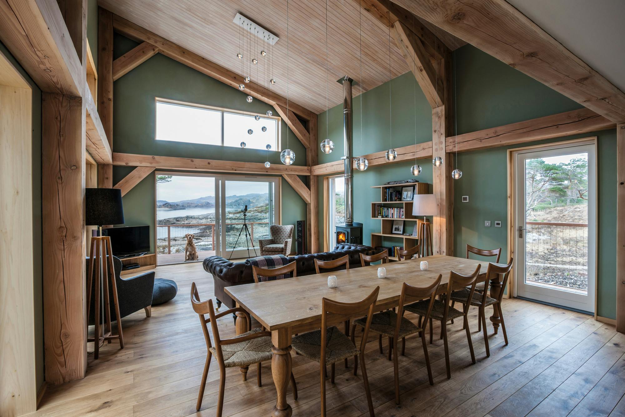 A dining table and sitting area with a log burner in a Douglas fir framed living room with a mono pitch