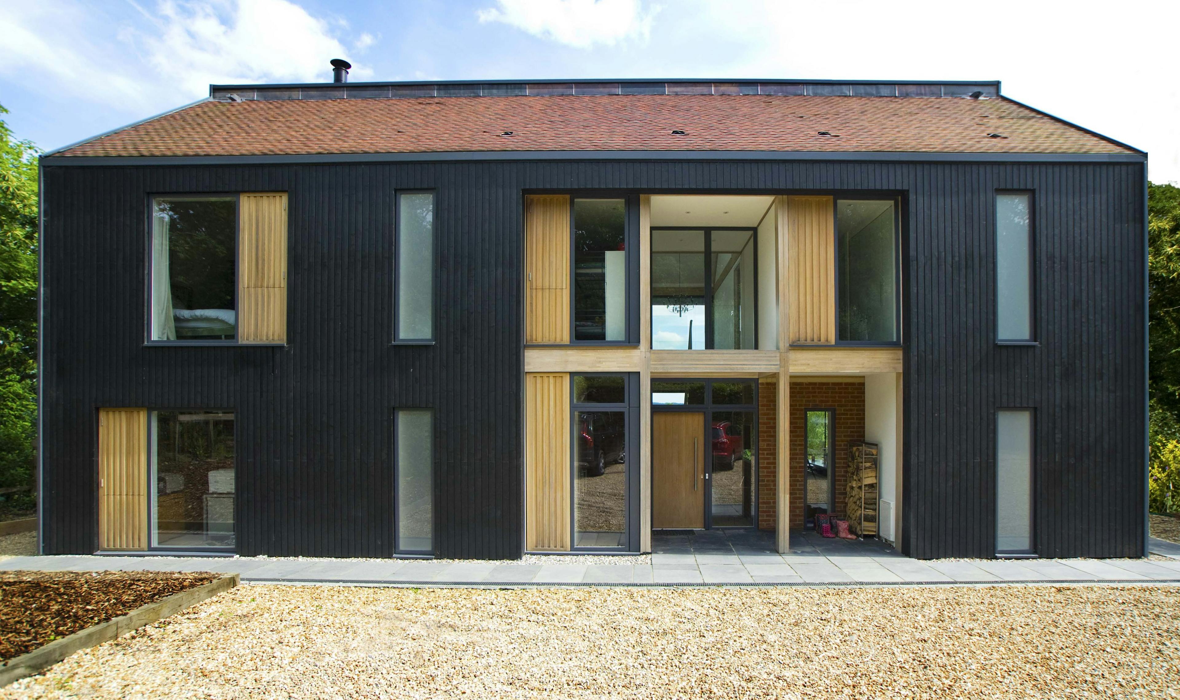 The front of a large black clad oak glulam framed house