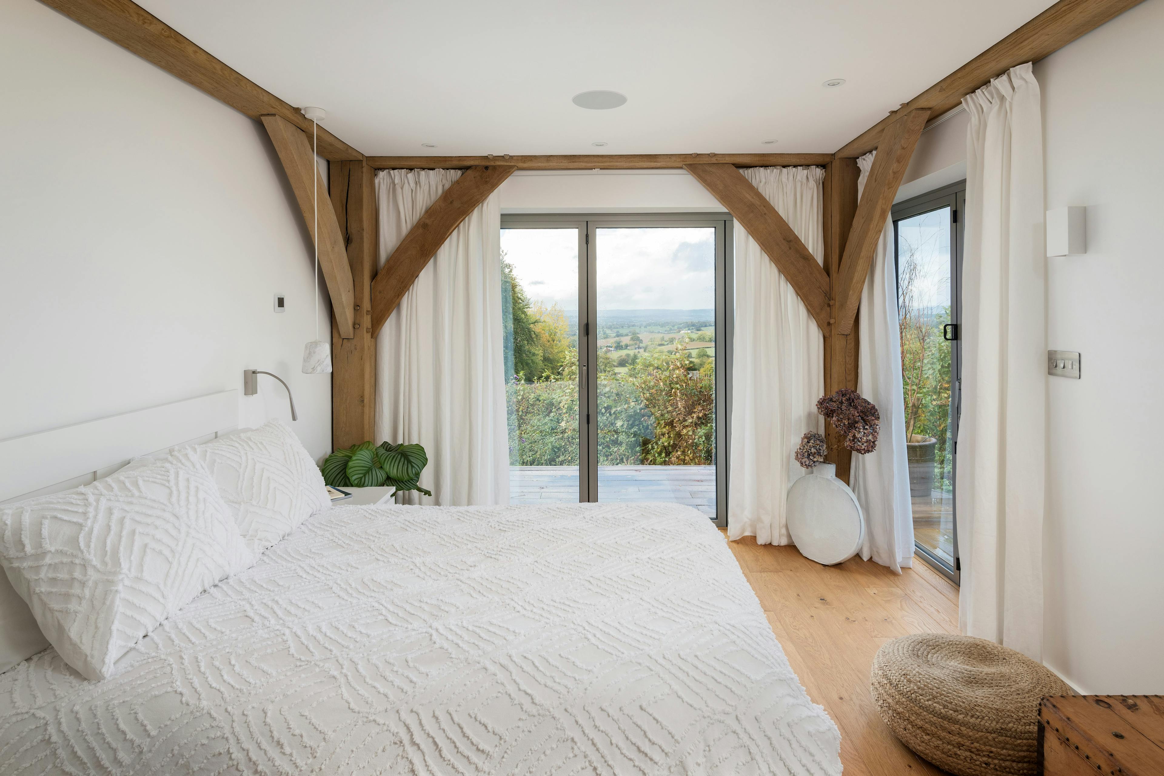 Oak framed bedroom with large glazed doors and views of the countryside
