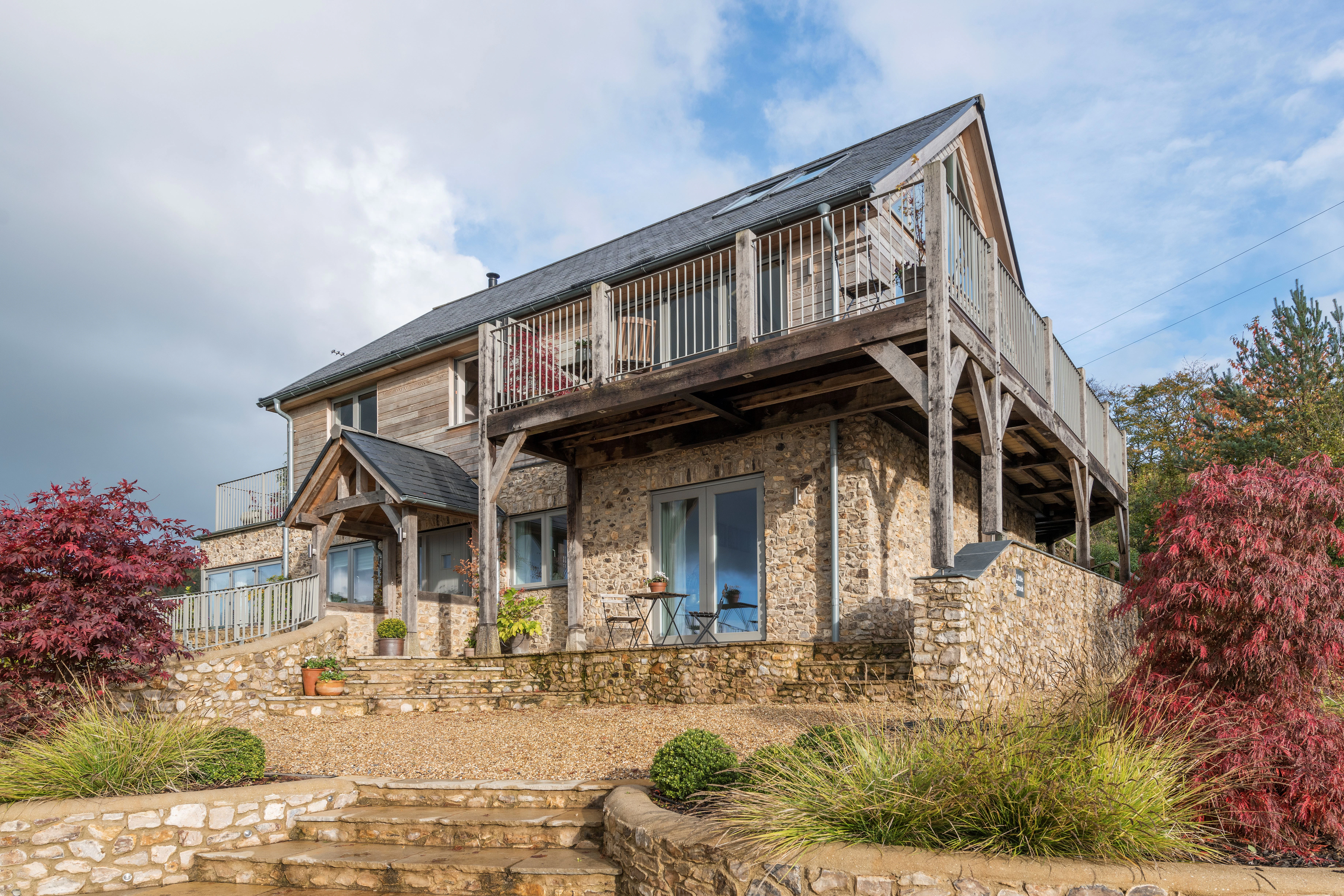External view of a timber clad oak framed house with oak balconies wrapping round