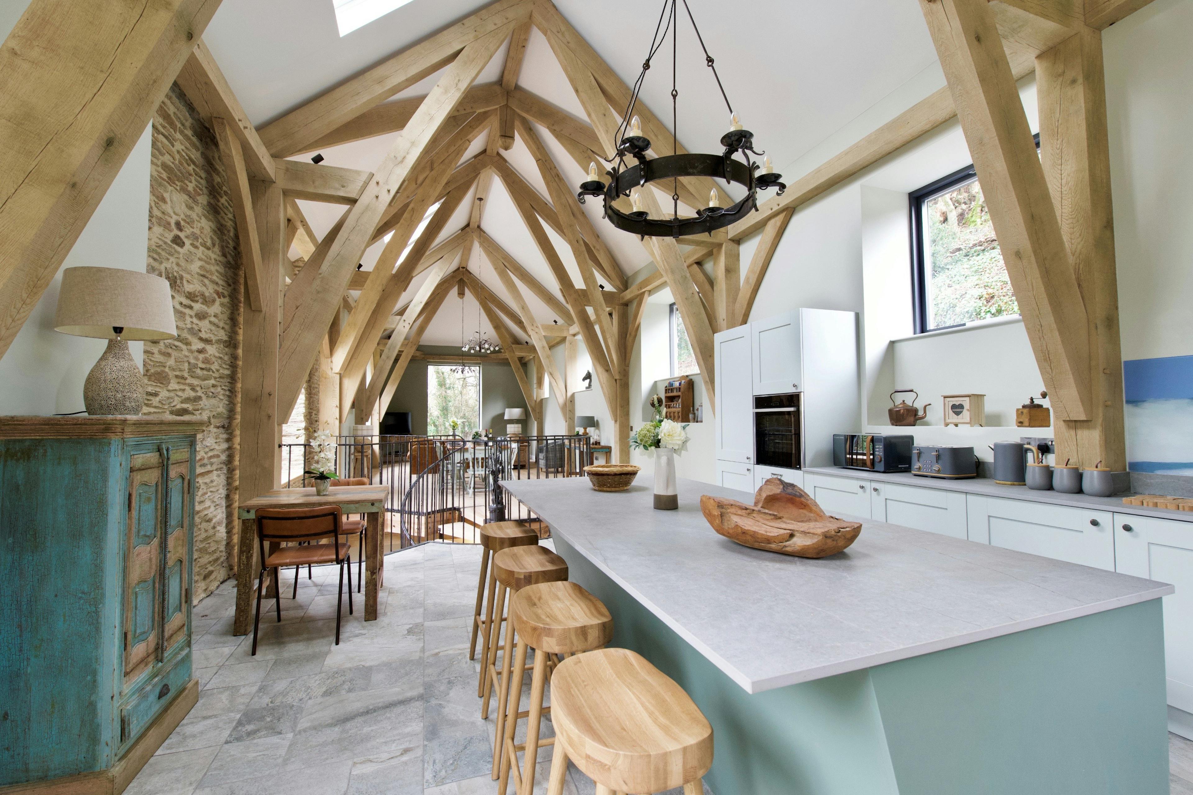 A vaulted oak framed open plan living room with a kitchen island and breakfast bar