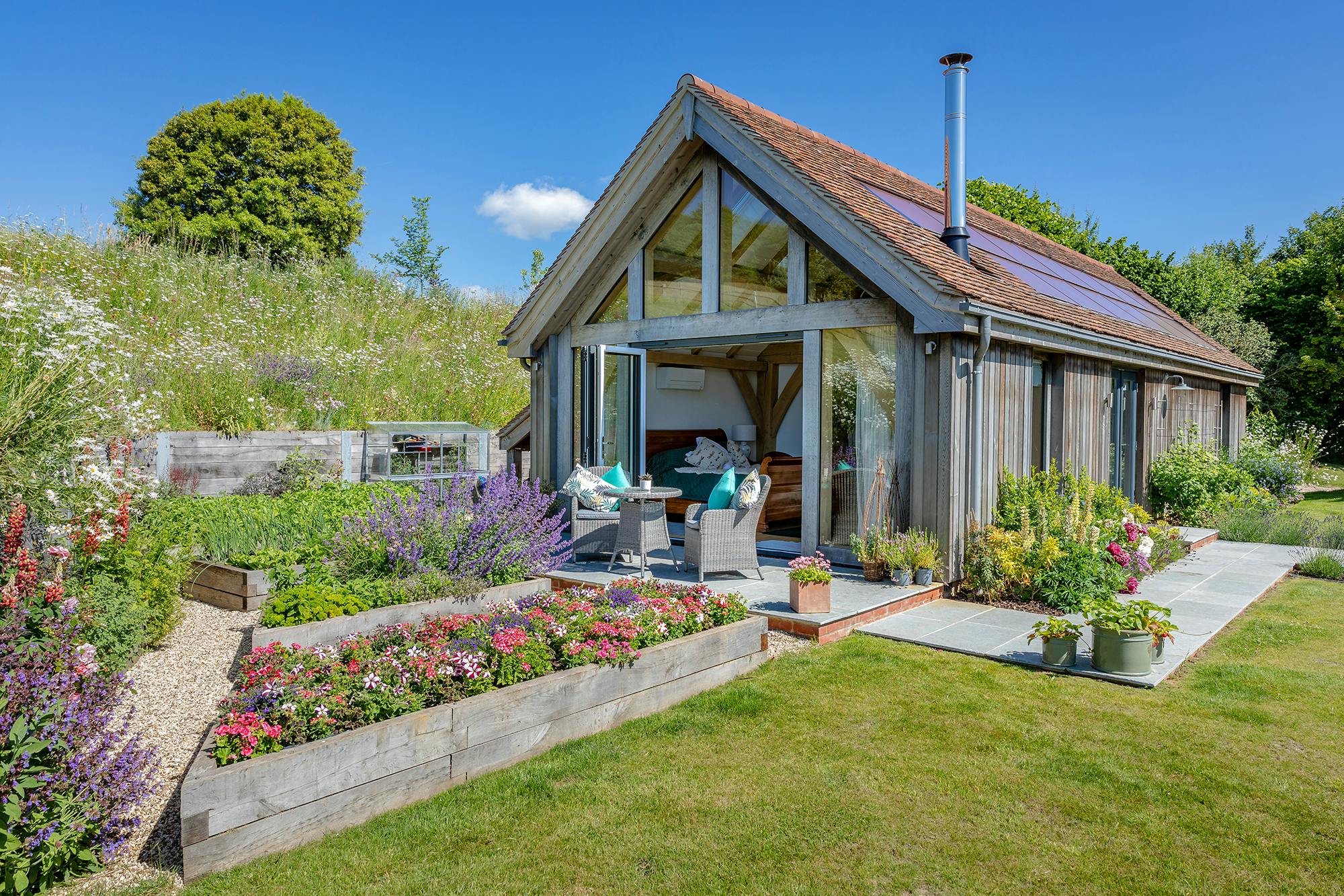 An oak framed garden annex with a glazed gable end and surrounded by a landscaped garden