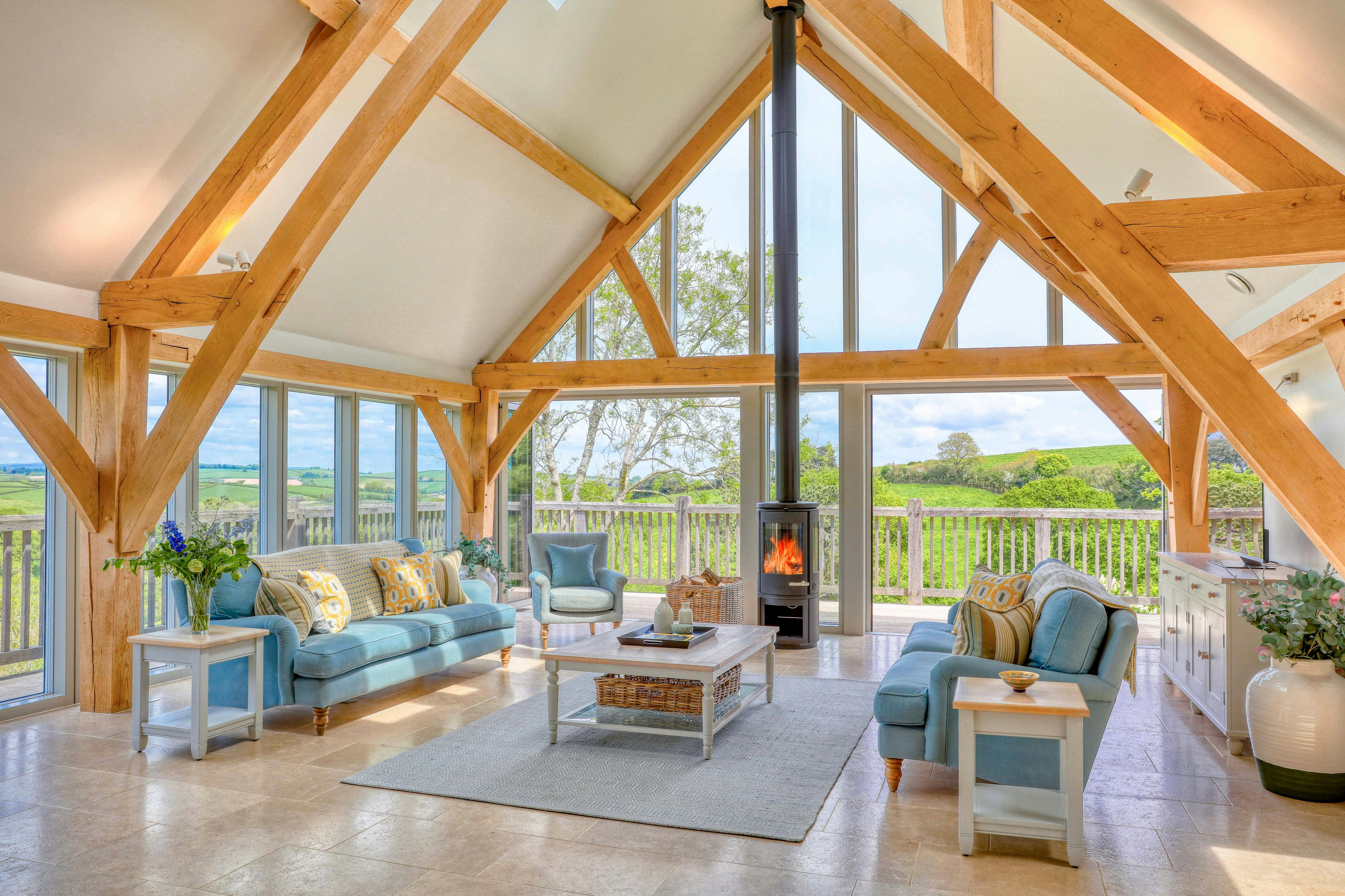 A sitting area with sofas and log burner in a vaulted an oak framed open plan living area