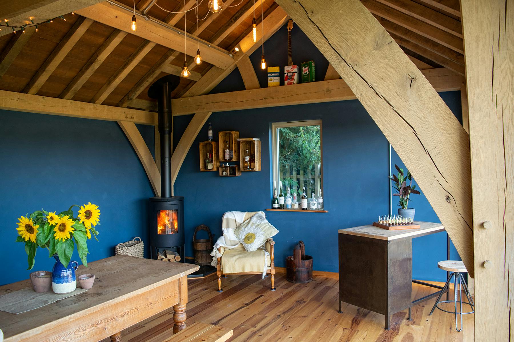 Oak framed living room with blue walls and a log burning stove