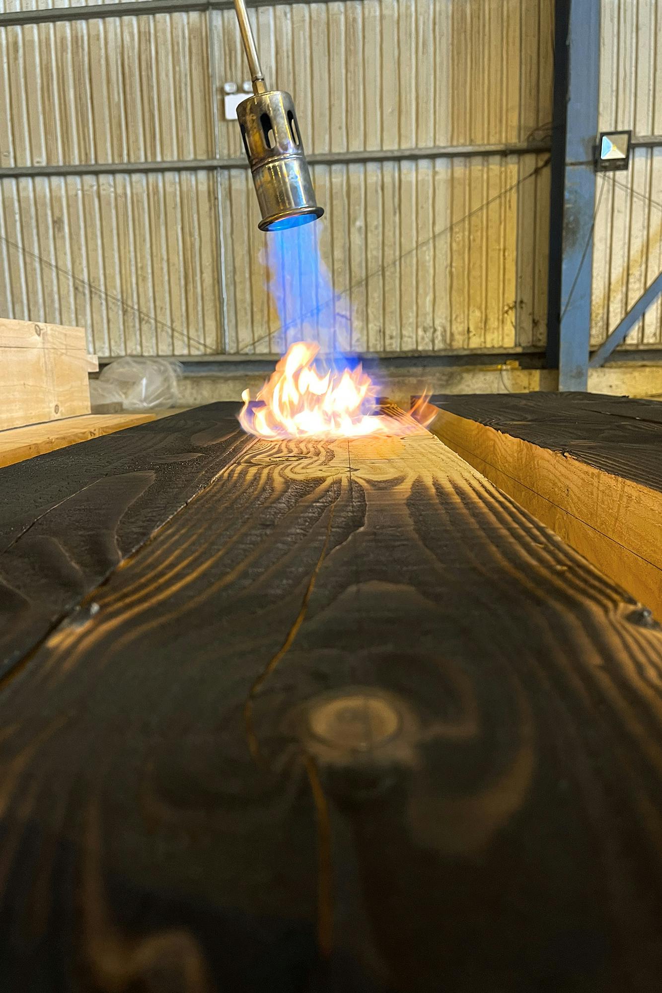 Timber being burnt with a blow torch
