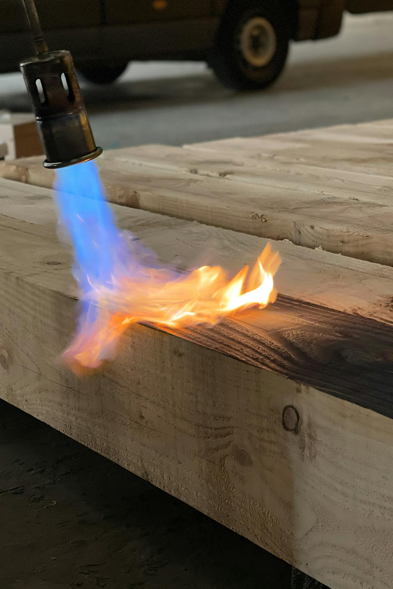 Timber being burnt with a blow torch