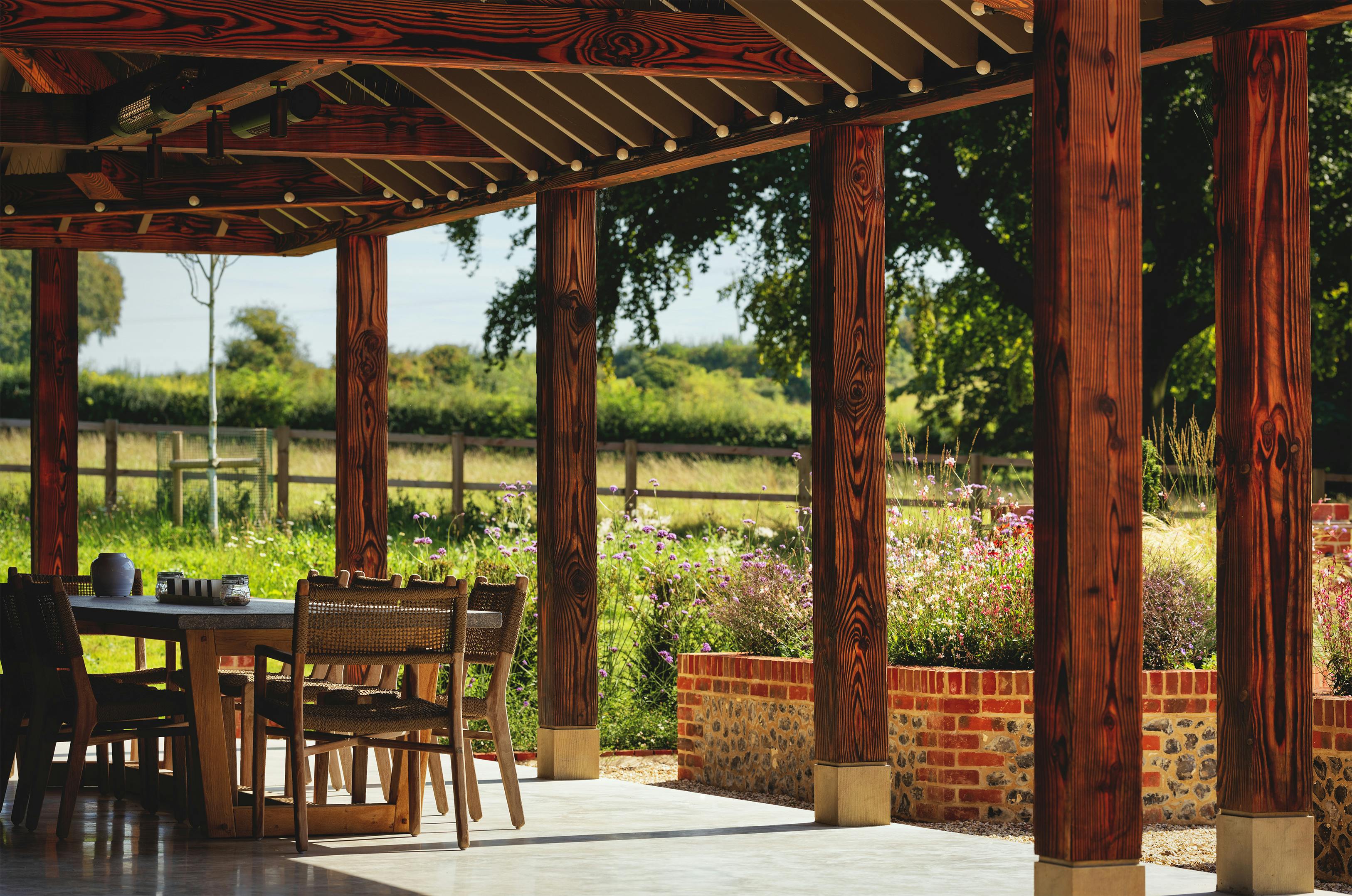 A charred Douglas fir frame outdoor structure showing dining table and chairs